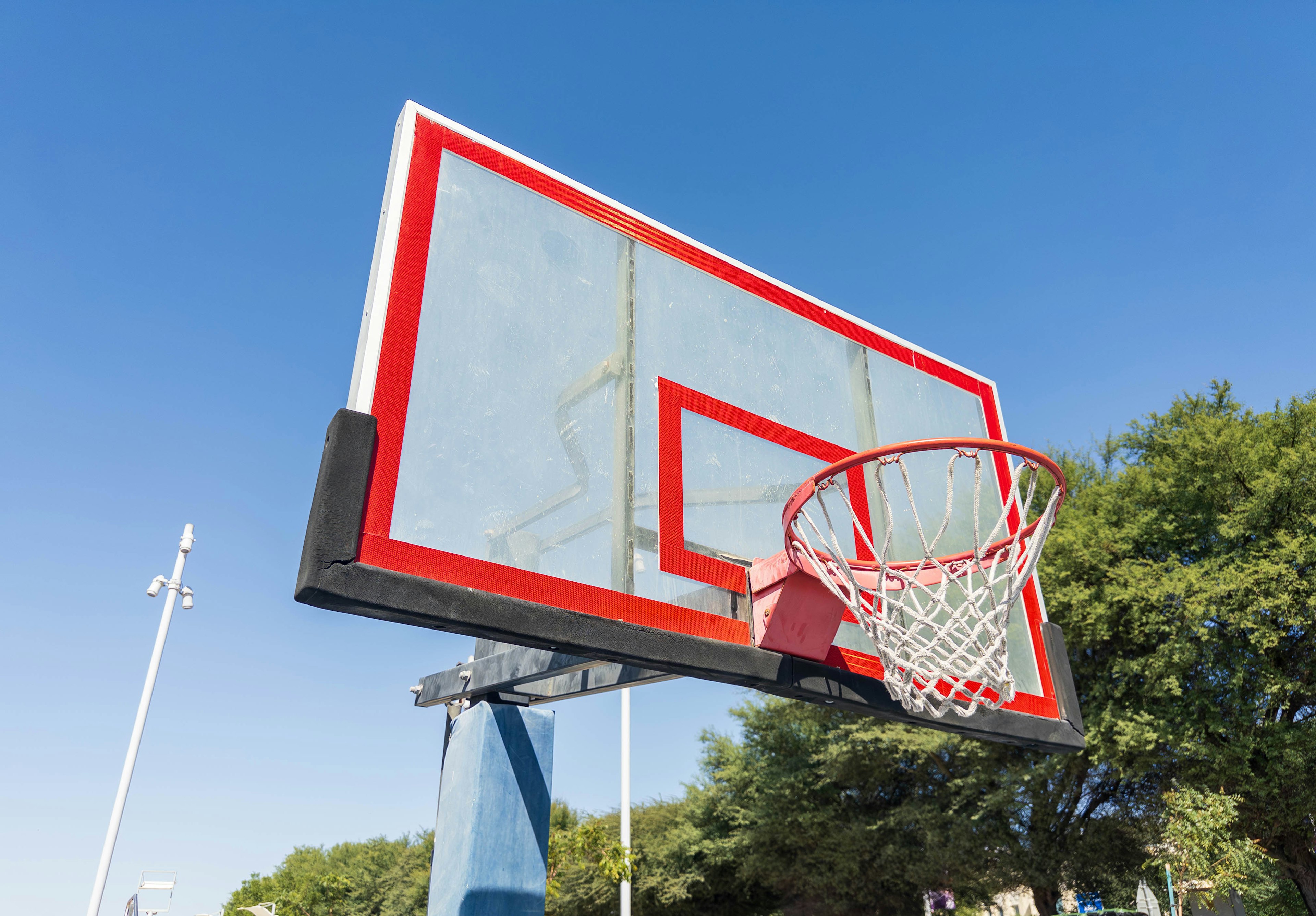 Canestro da basket rosso e tabellone sotto un cielo blu chiaro