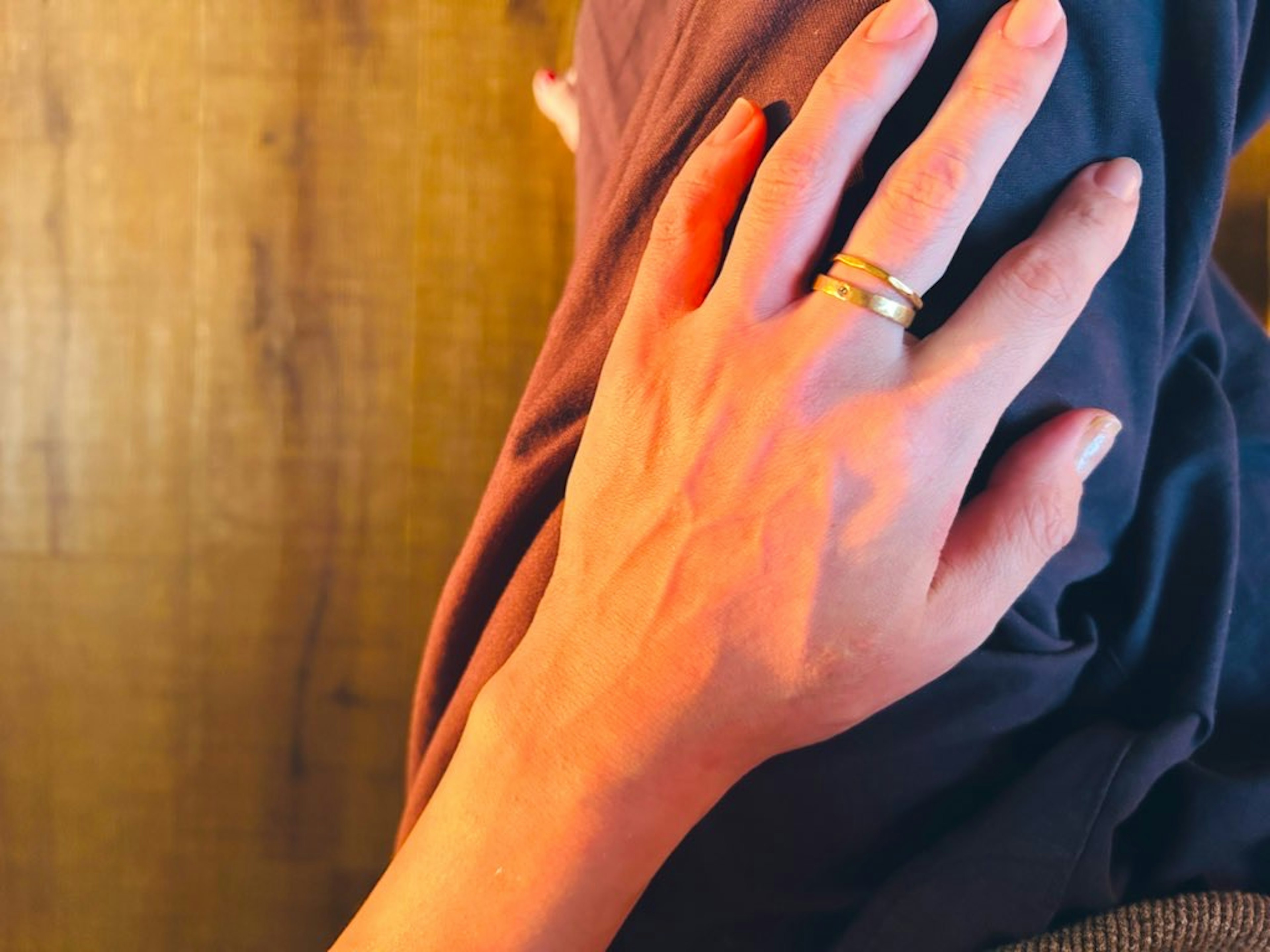 A hand resting on a knee with a ring on the fingers