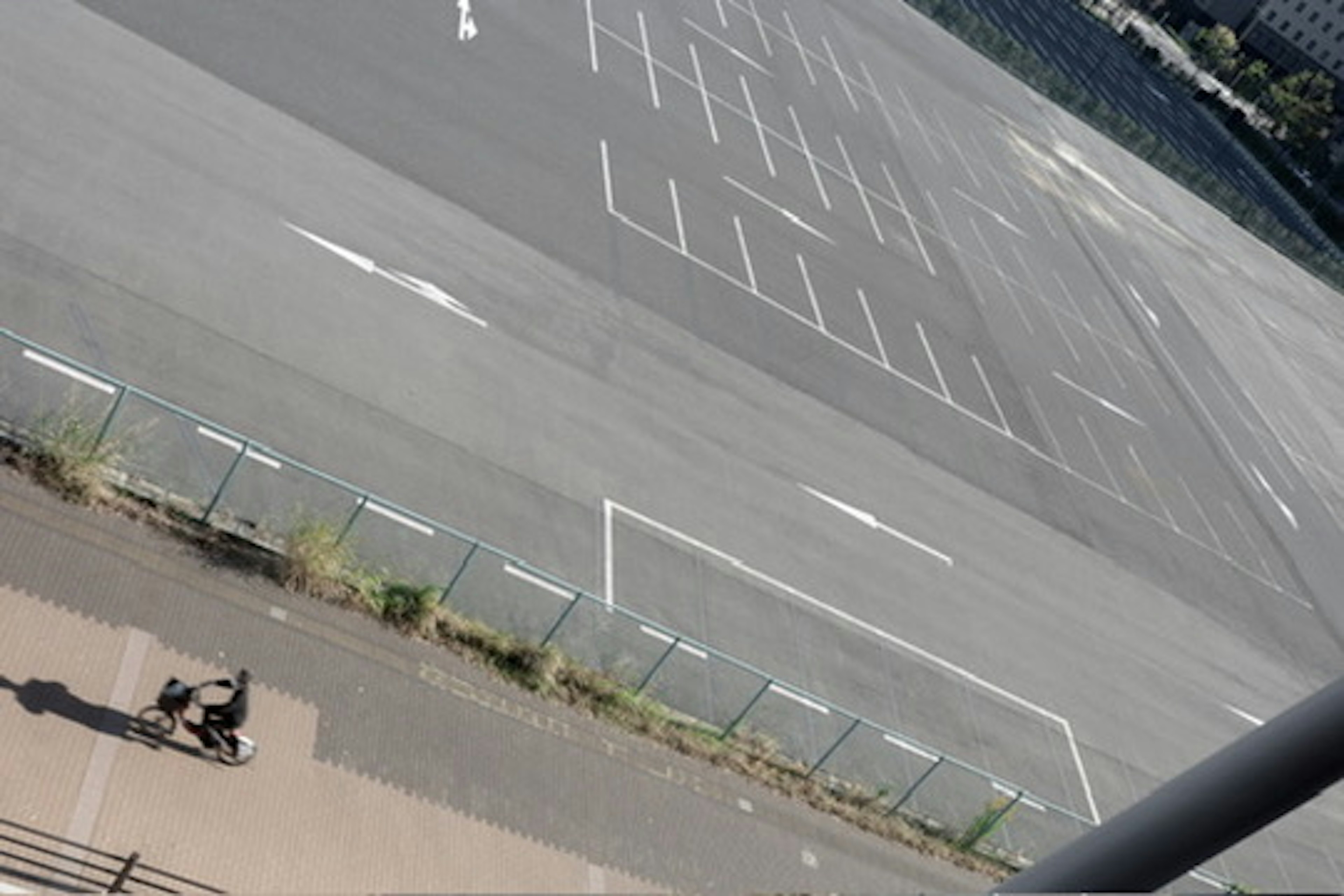 空の駐車場と自転車に乗る人