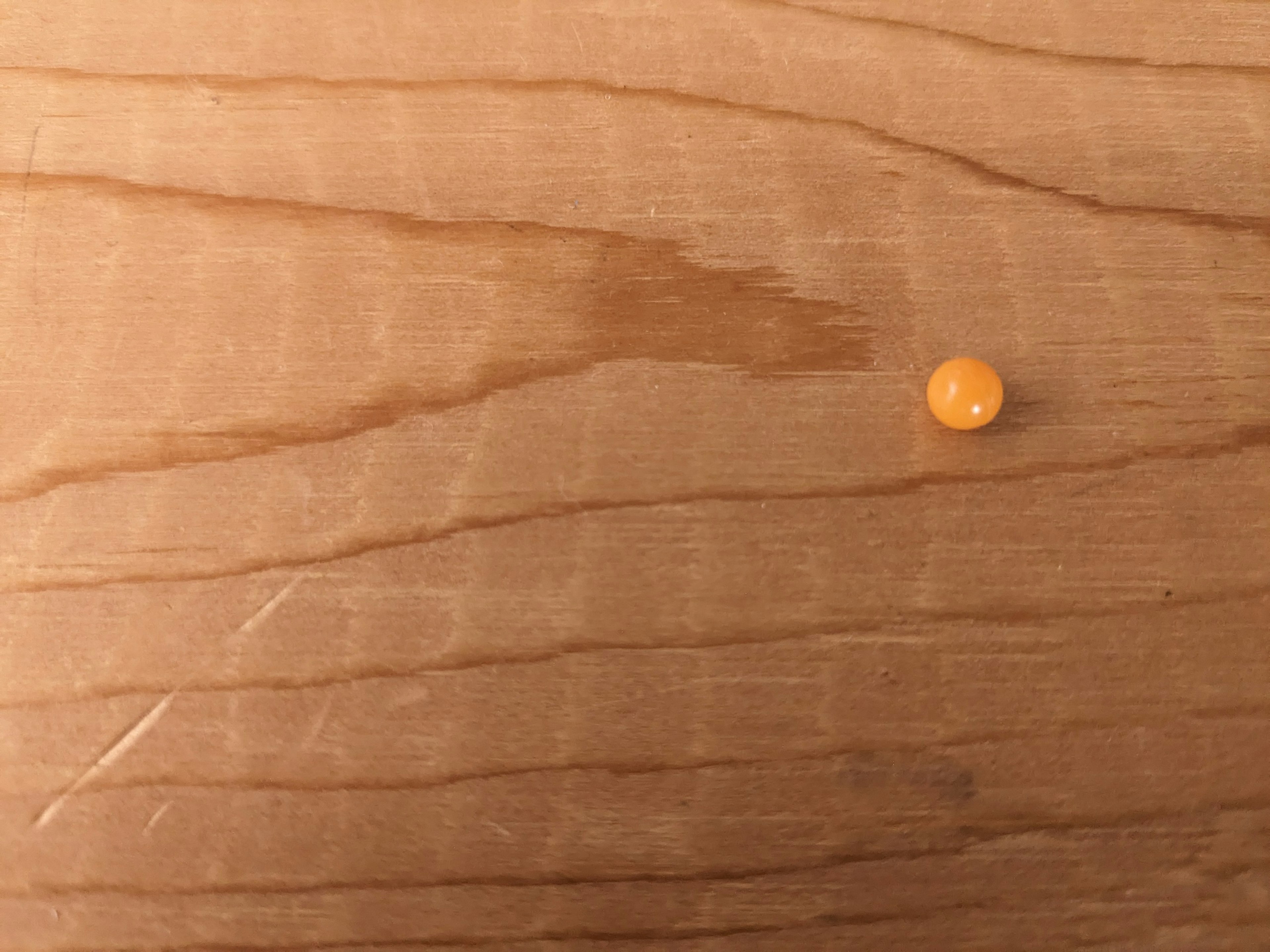 Pequeña bola naranja sobre una mesa de madera