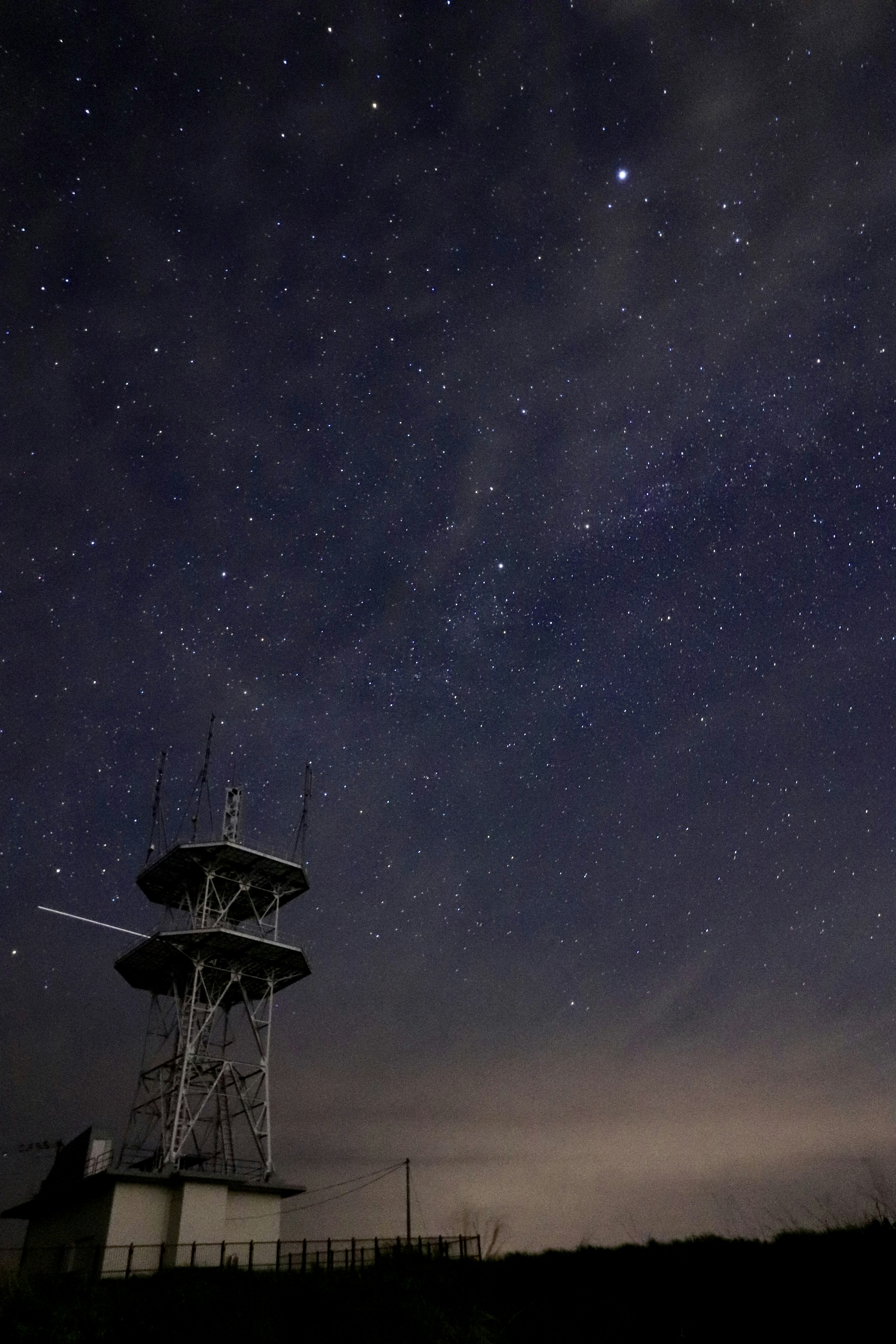 Cielo notturno pieno di stelle sopra una torre di comunicazione