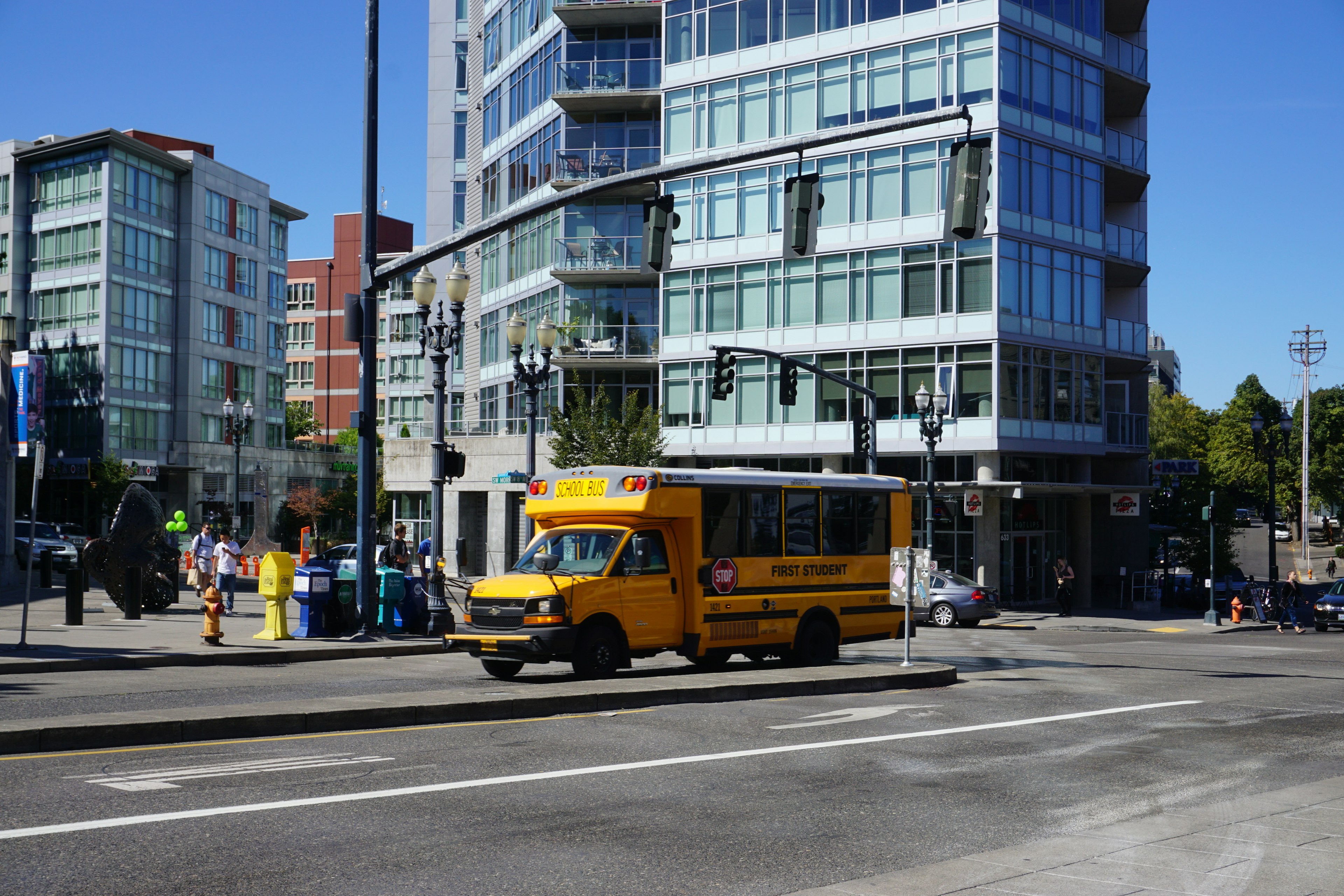 Un autobus giallo che attraversa un incrocio urbano con edifici moderni