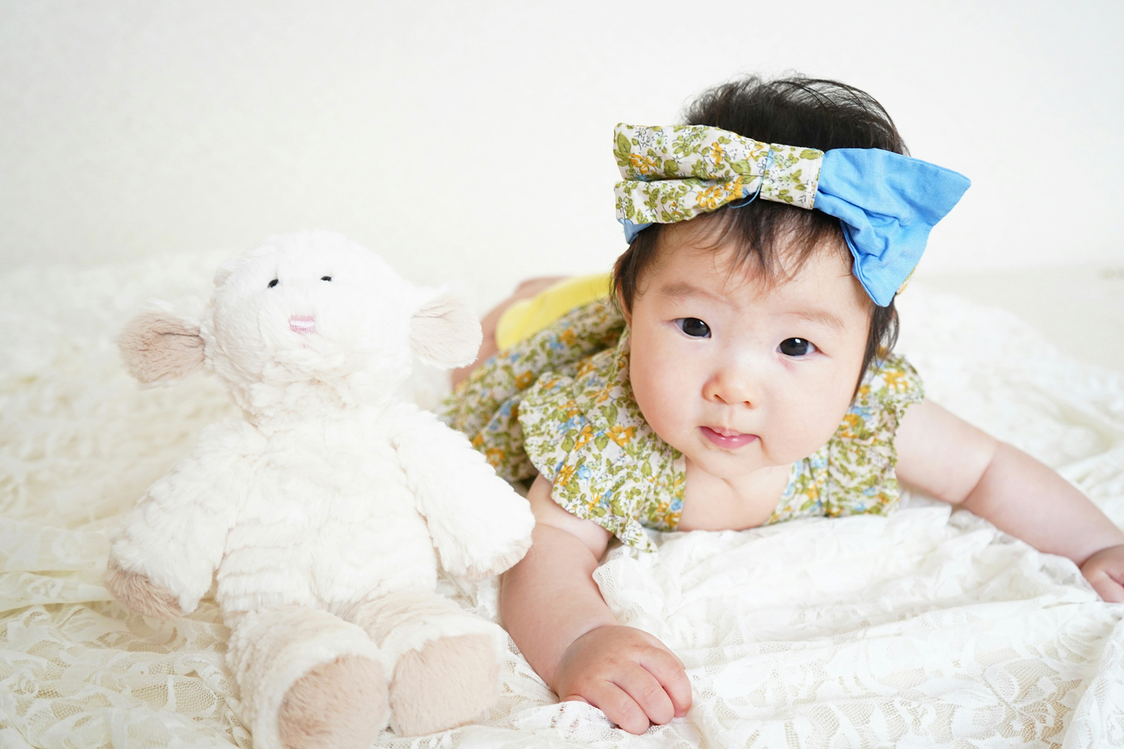 Baby lying on a blanket with a white stuffed lamb