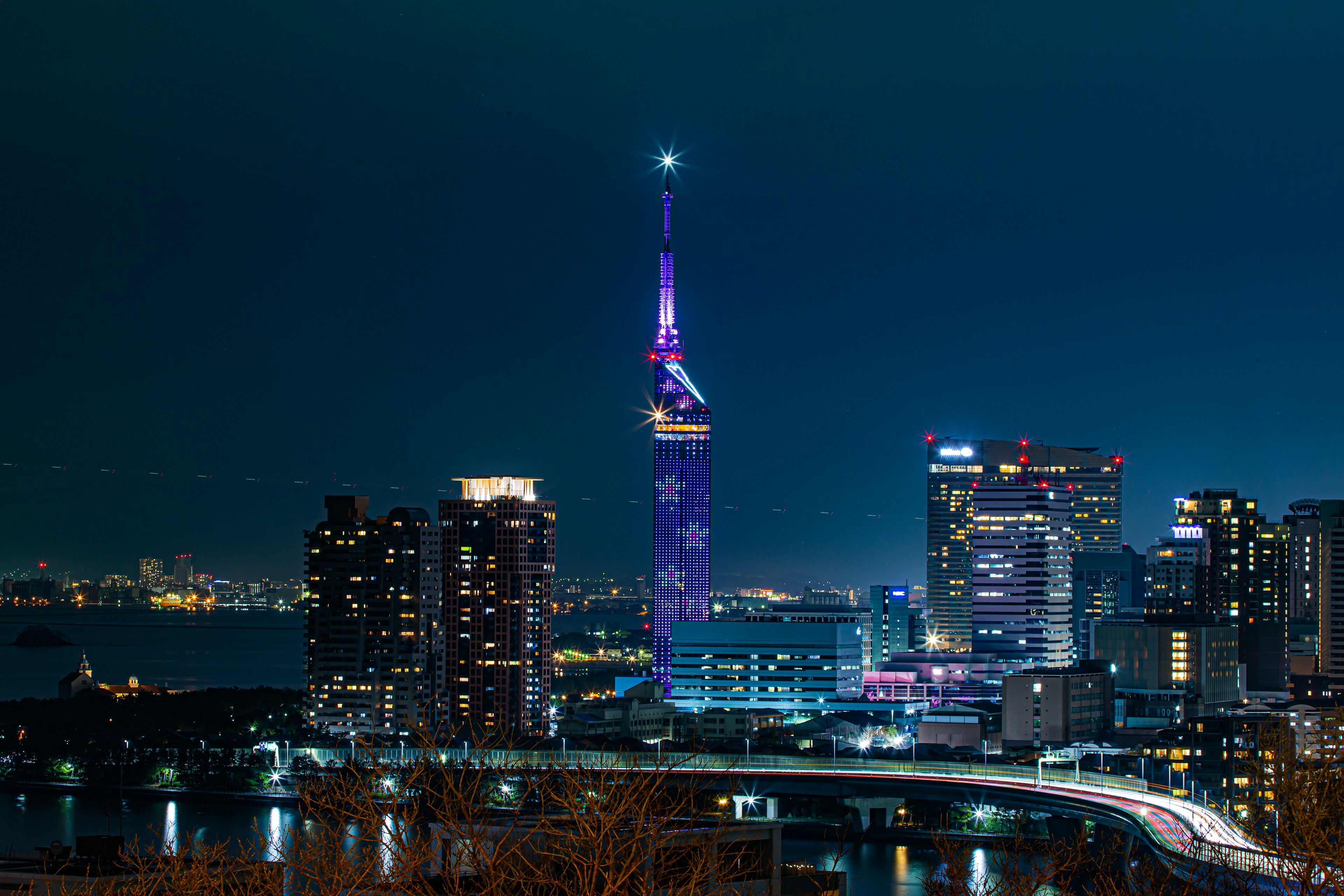 Fukuoka Tower illuminated at night with surrounding skyscrapers