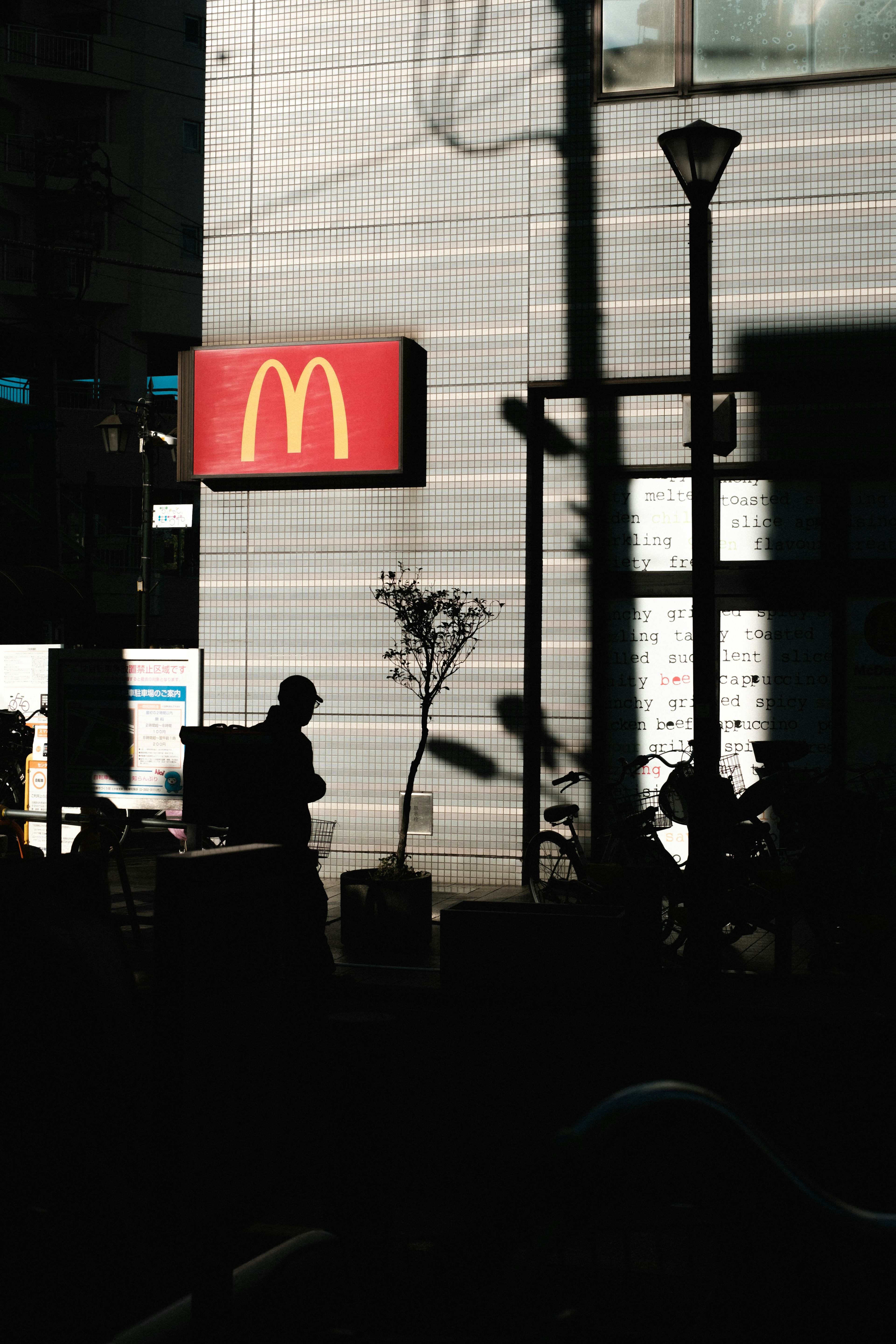 Silhouette di una persona vicino a un'insegna McDonald's di notte