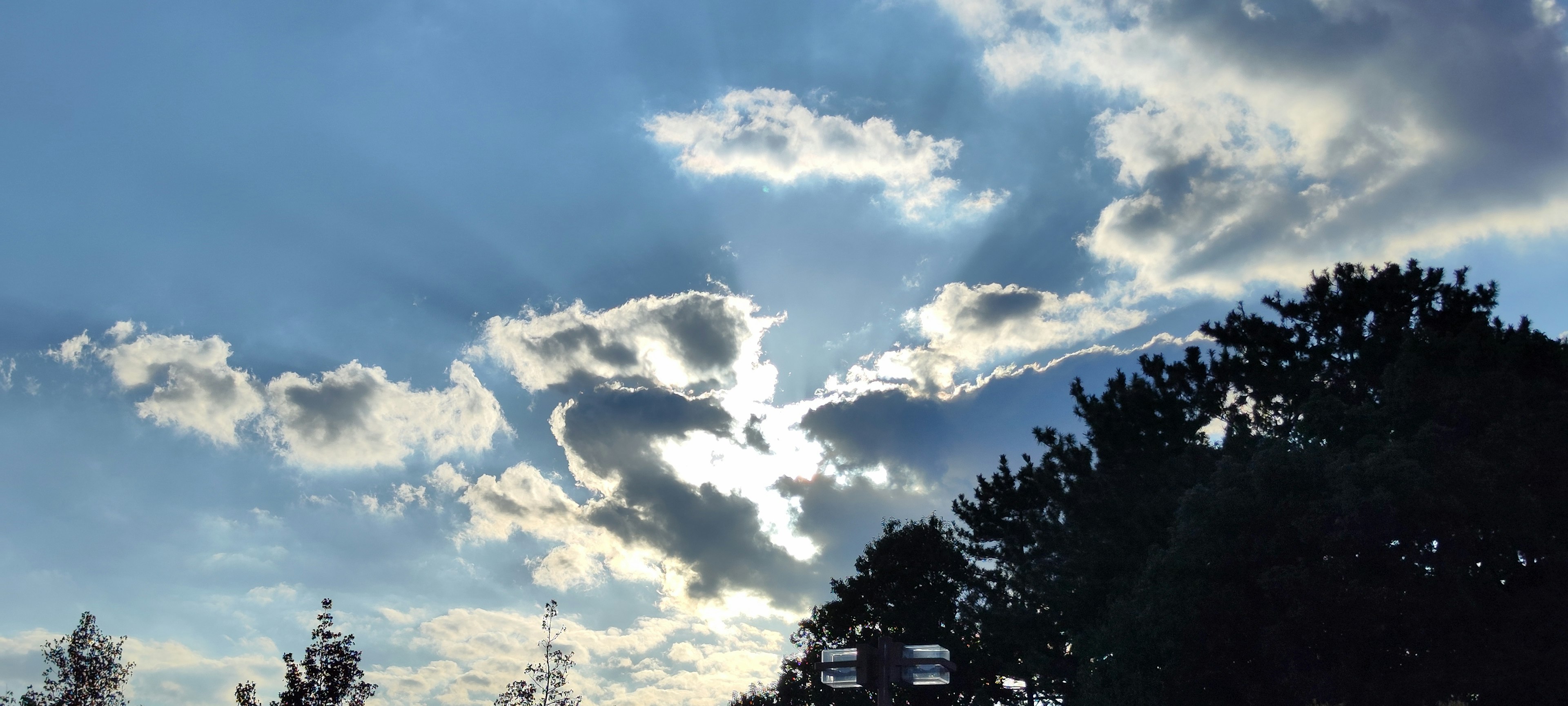 Una vista panoramica di nuvole e luce solare che attraversano un cielo azzurro