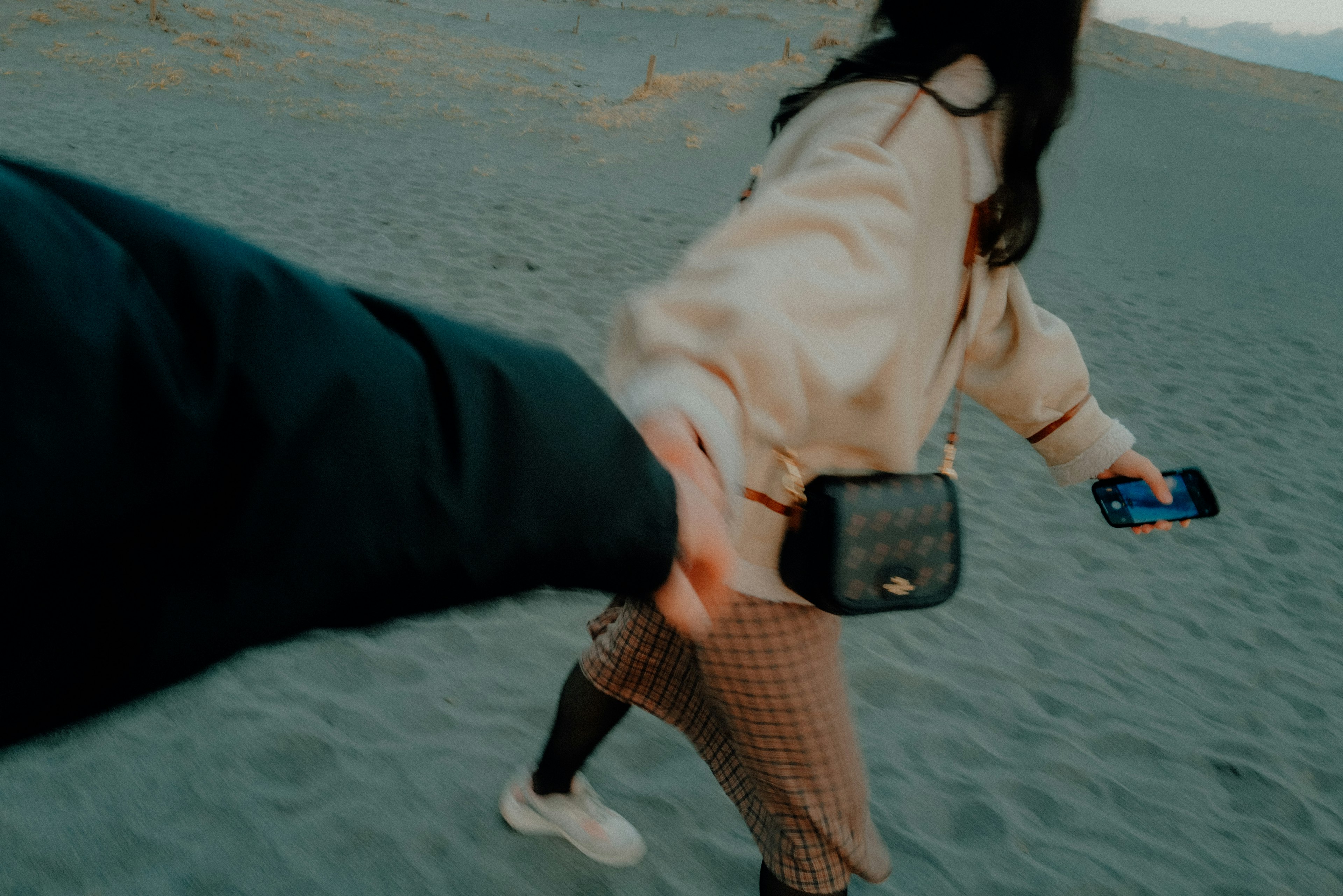 Couple holding hands while walking on a sandy beach