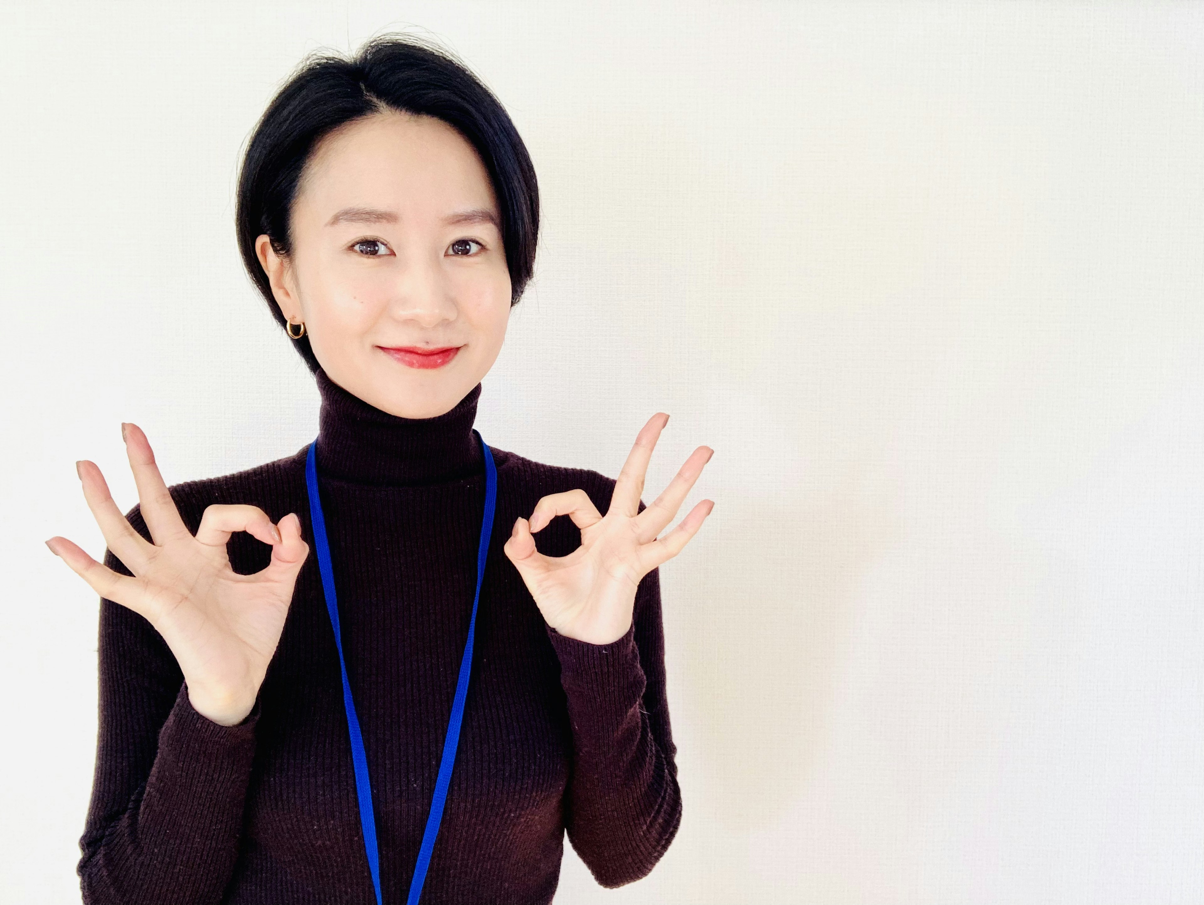 A woman in a black turtleneck making OK signs with both hands