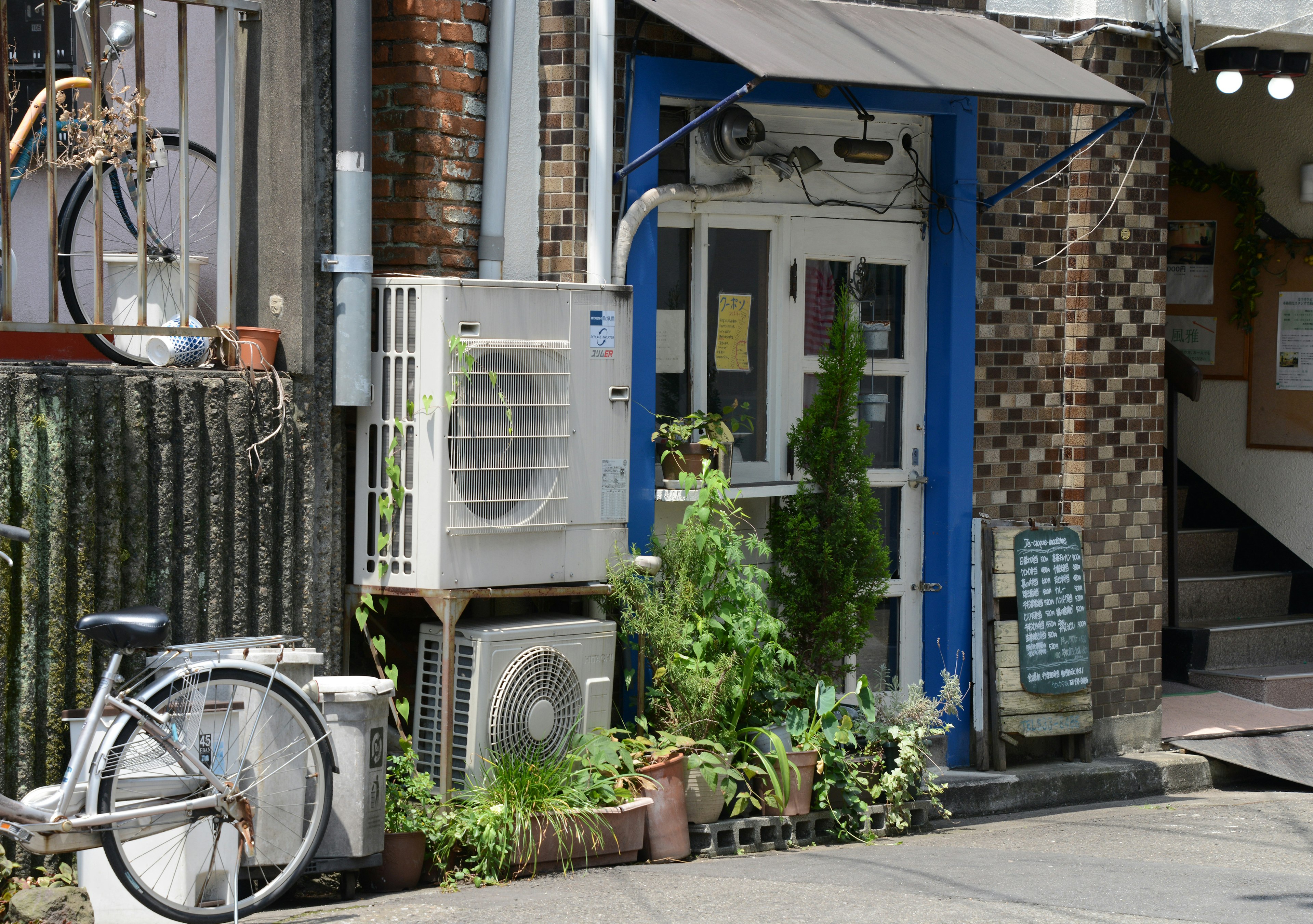 Exterior of a small cafe with blue door and plants