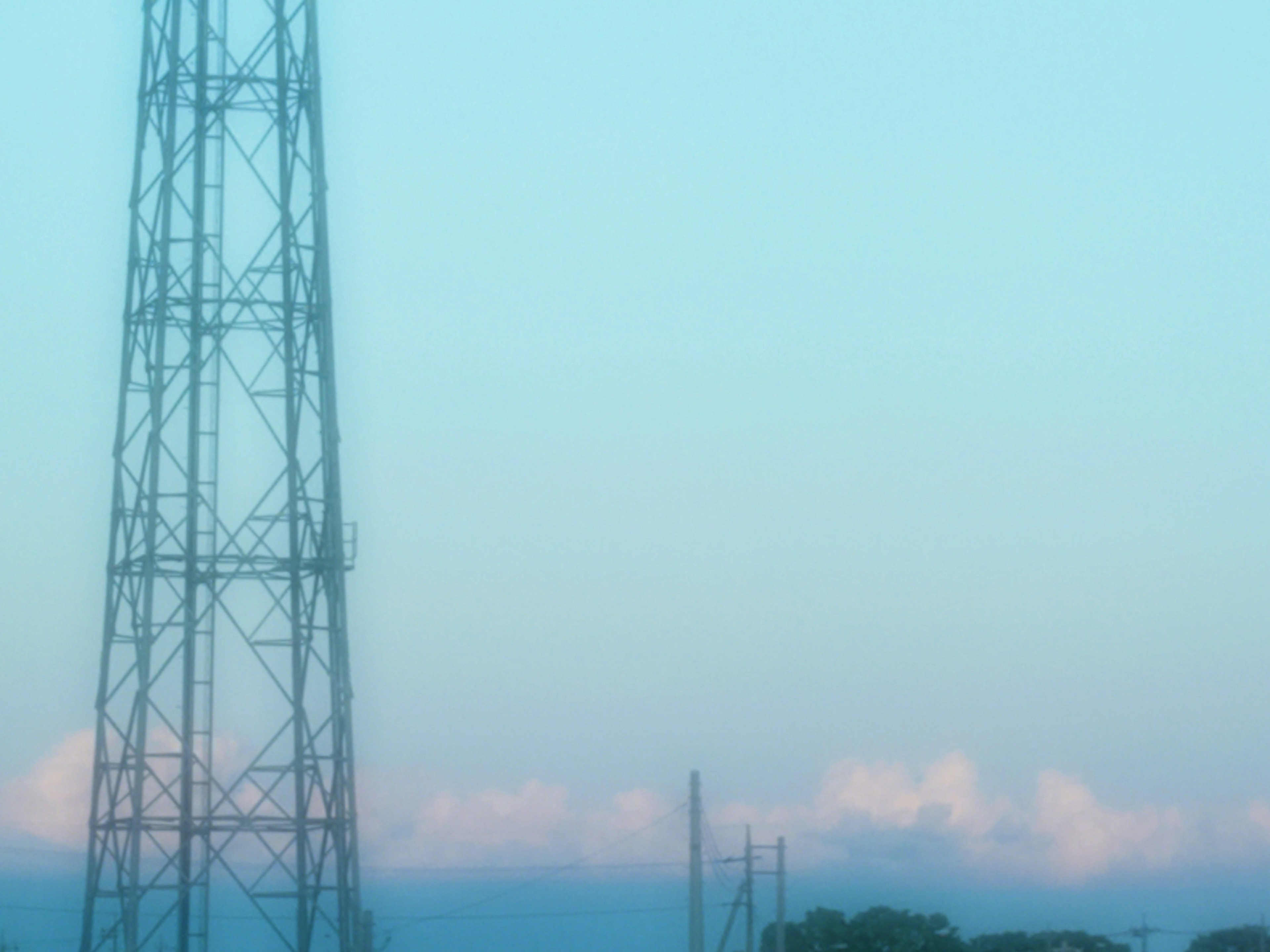 薄明かりの中に立つ通信塔と柔らかな雲の風景