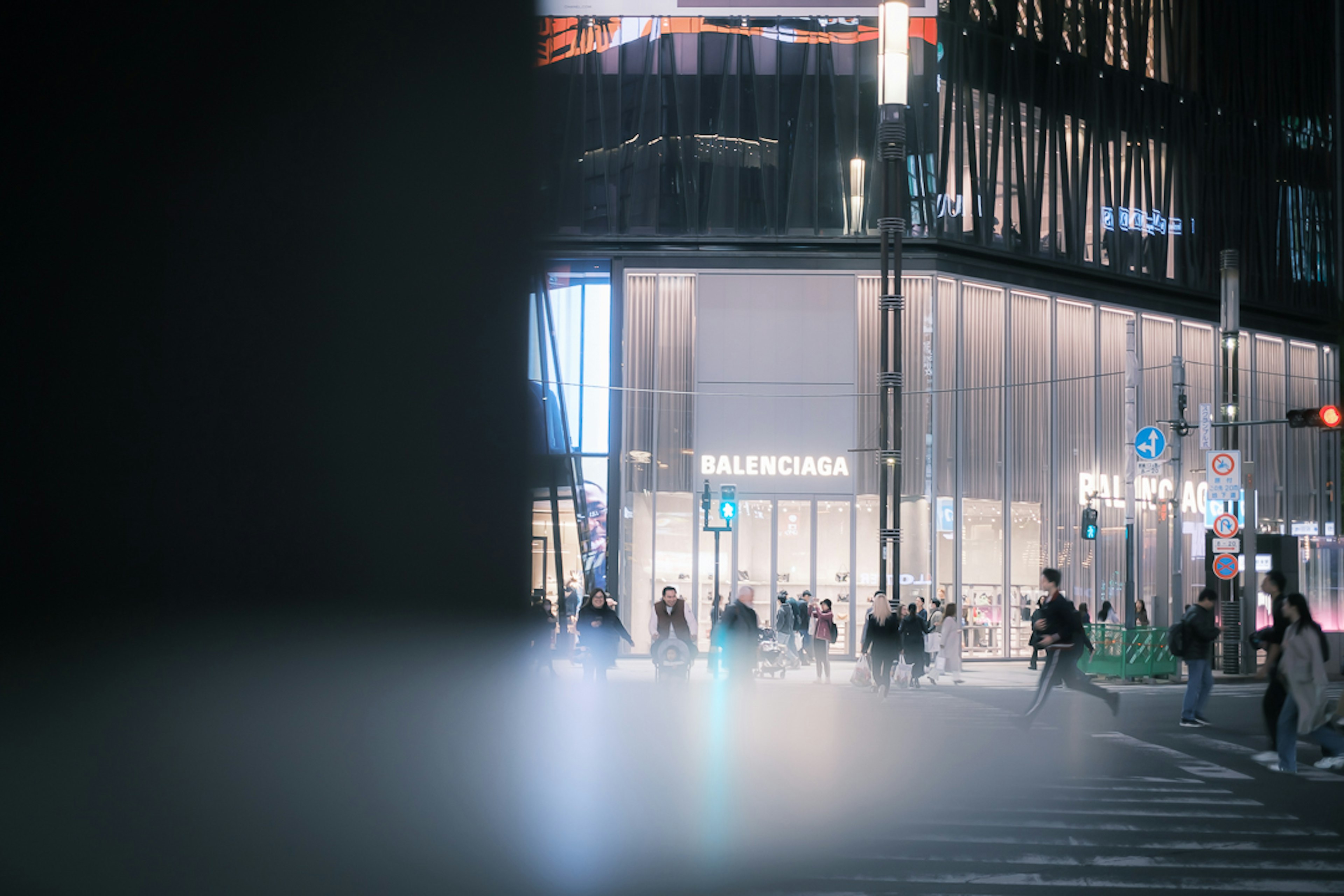 Personas cruzando la calle de noche con escaparates iluminados