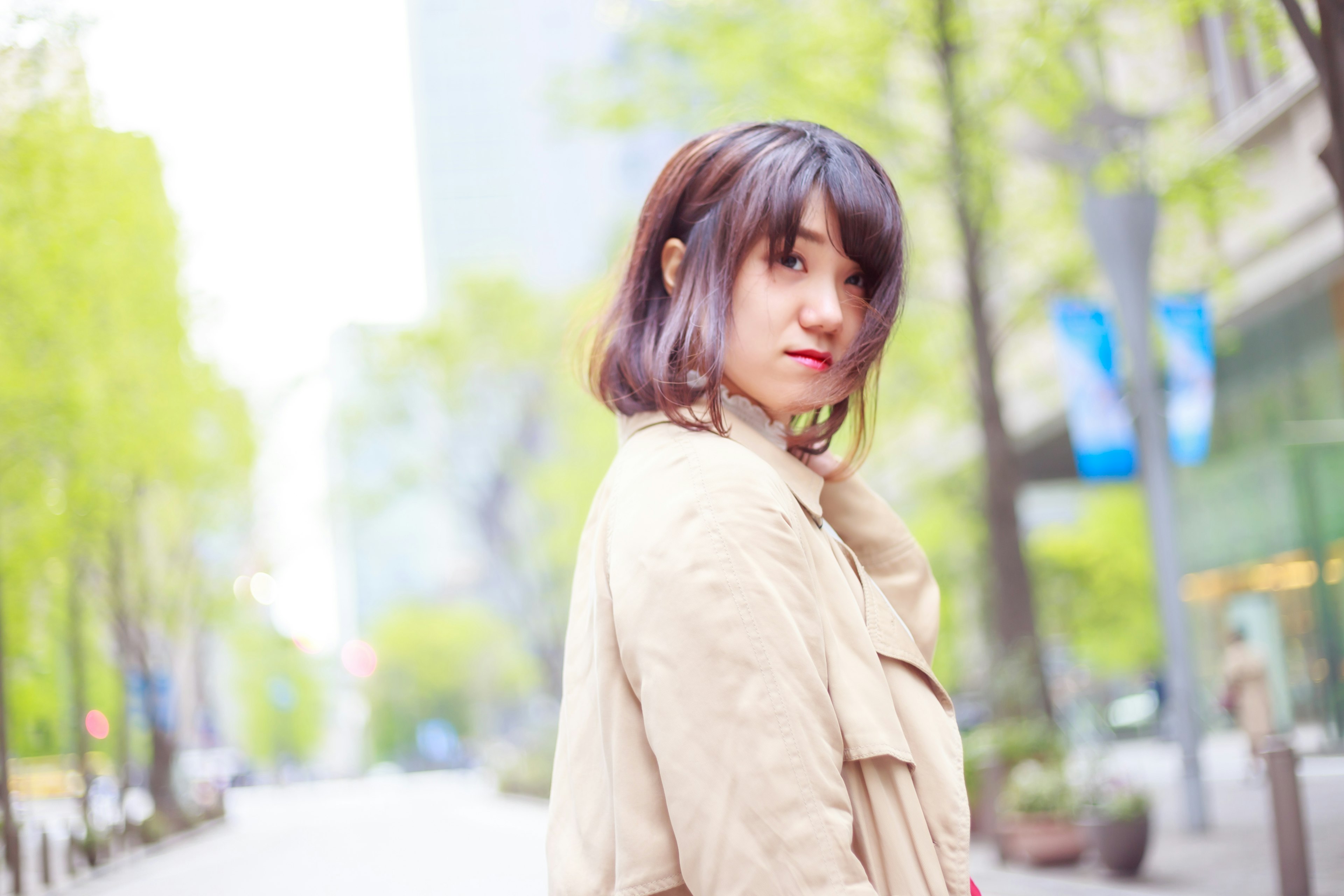 Portrait of a woman turning around on a city street surrounded by spring greenery