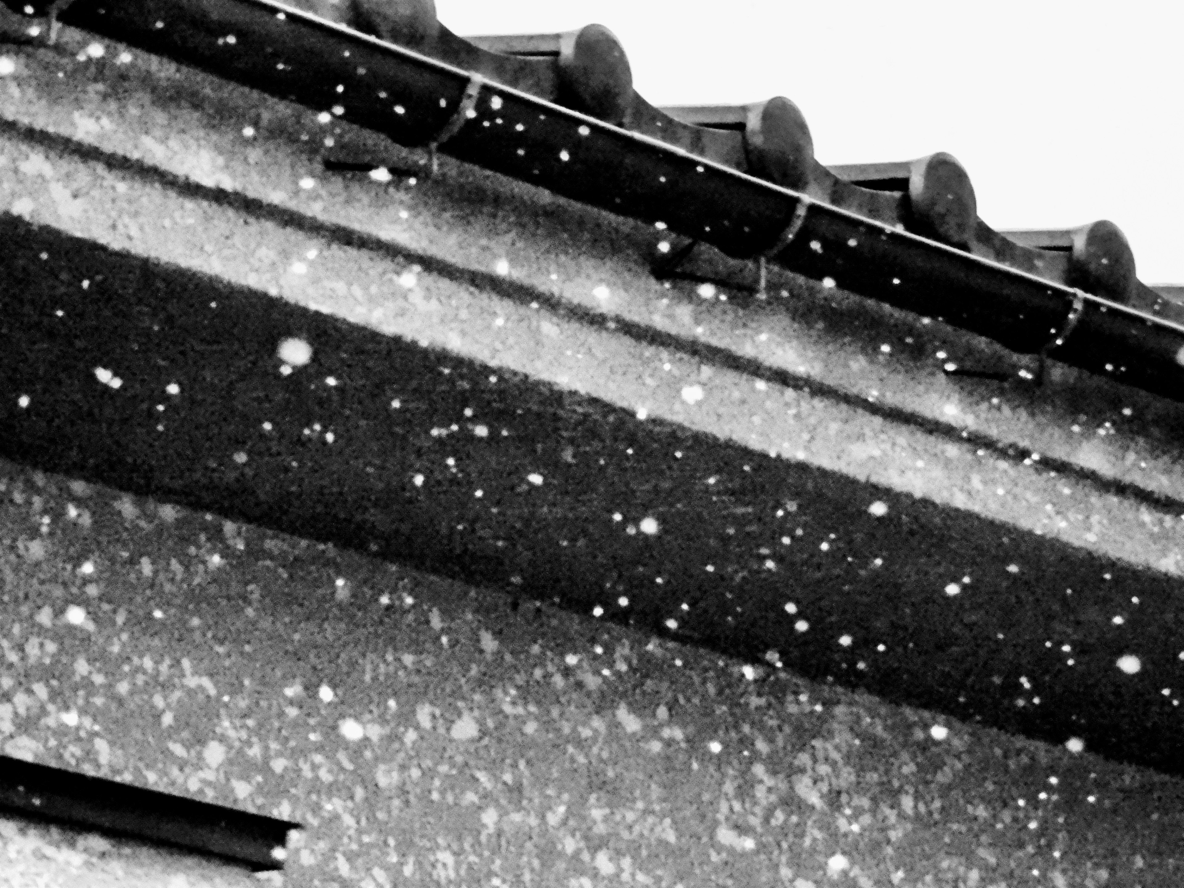 Image en noir et blanc de flocons de neige tombant sur un toit