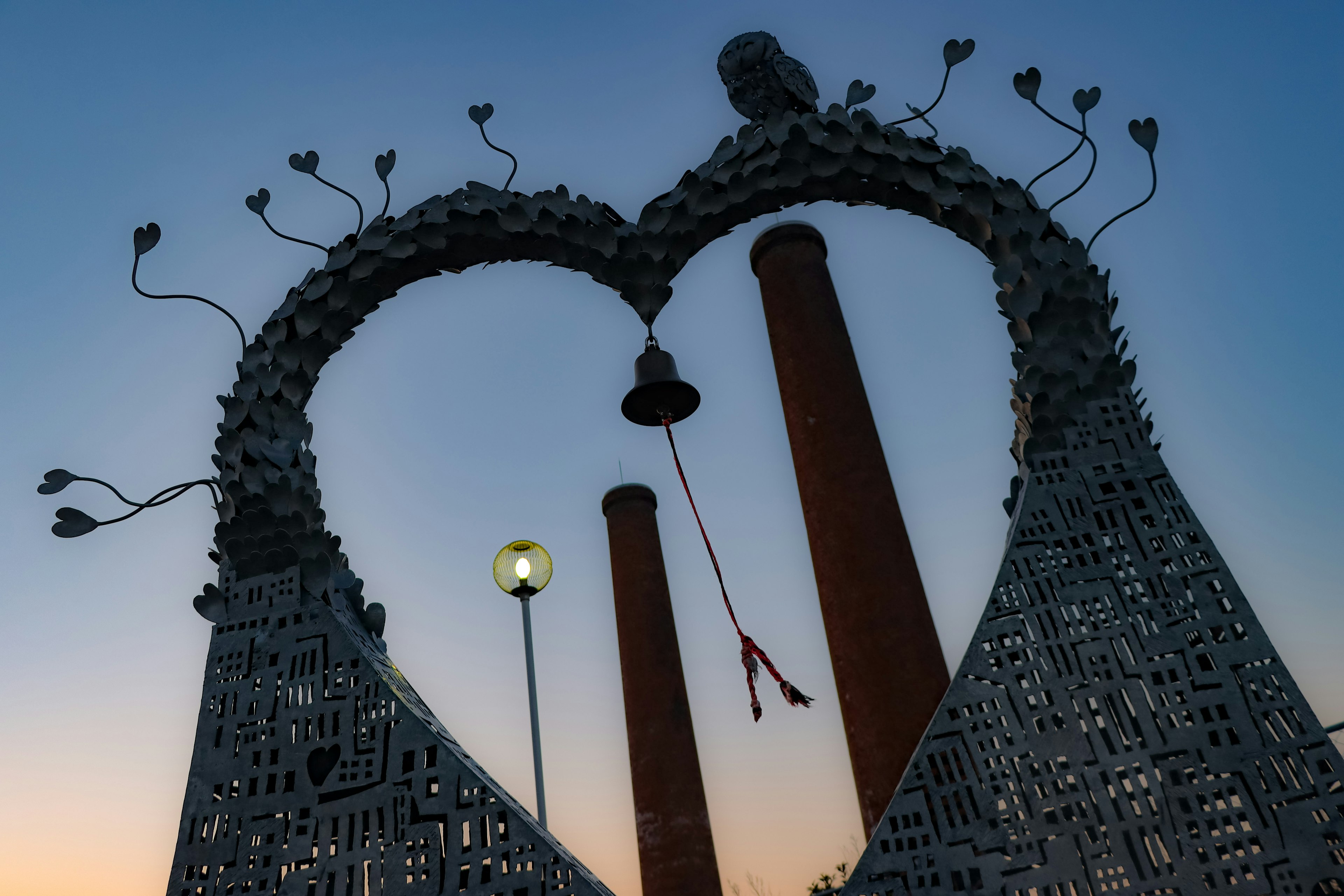 Arco a forma di cuore con una campana e camini al tramonto