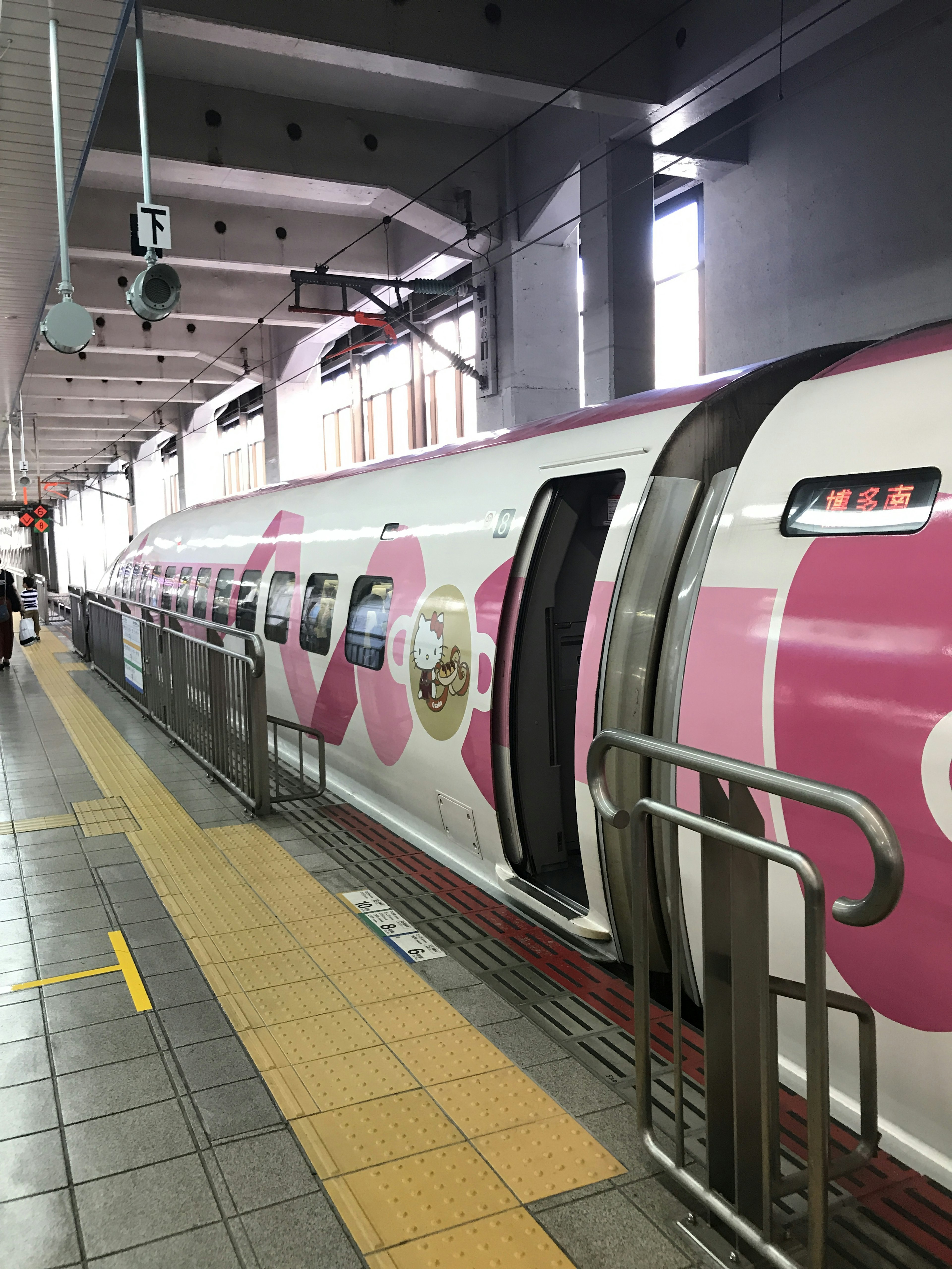 Ein rosa gestalteter Shinkansen-Zug auf einem Bahnhofsgleis