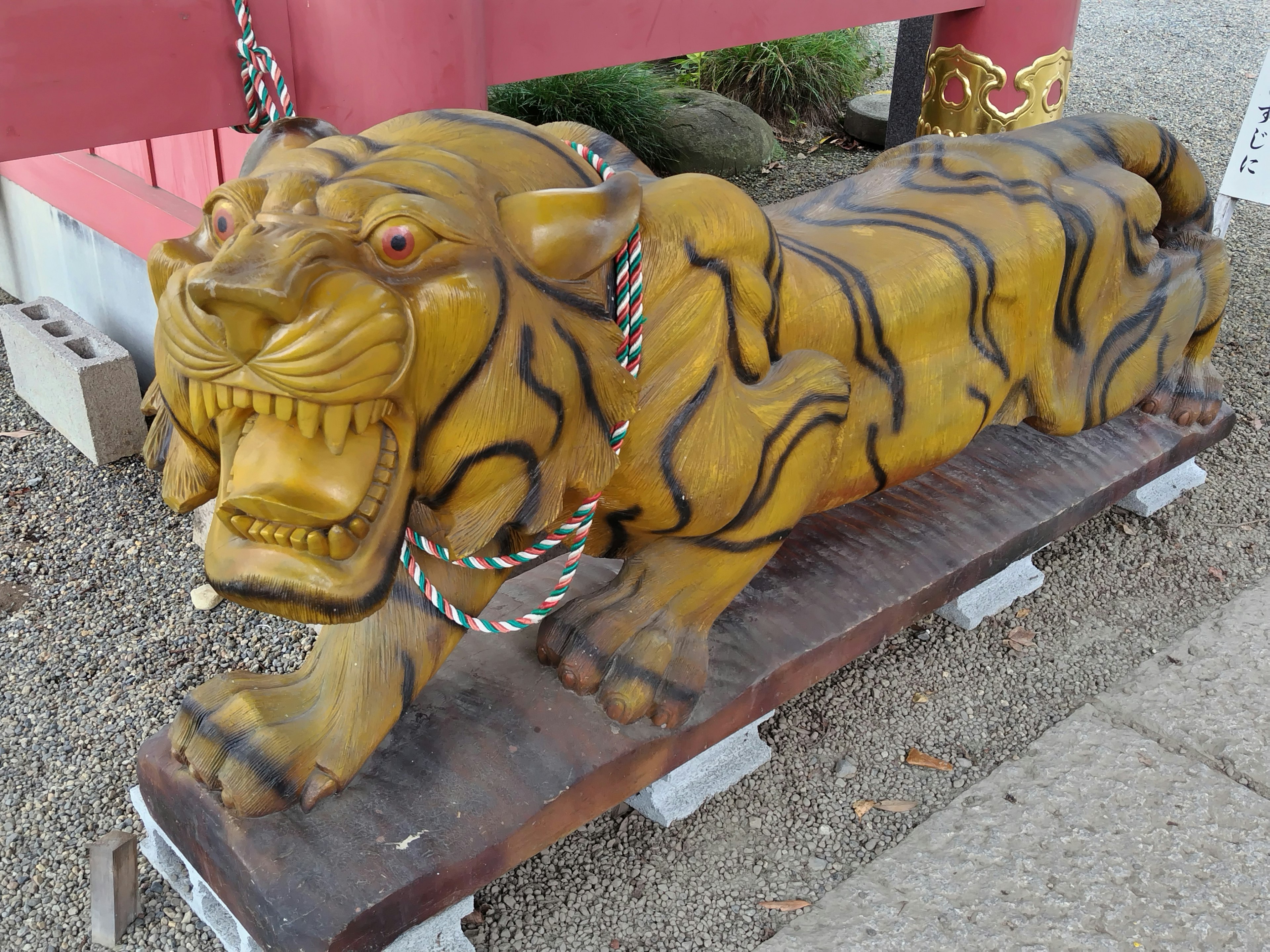 Wooden tiger sculpture with intricate details on a platform chained