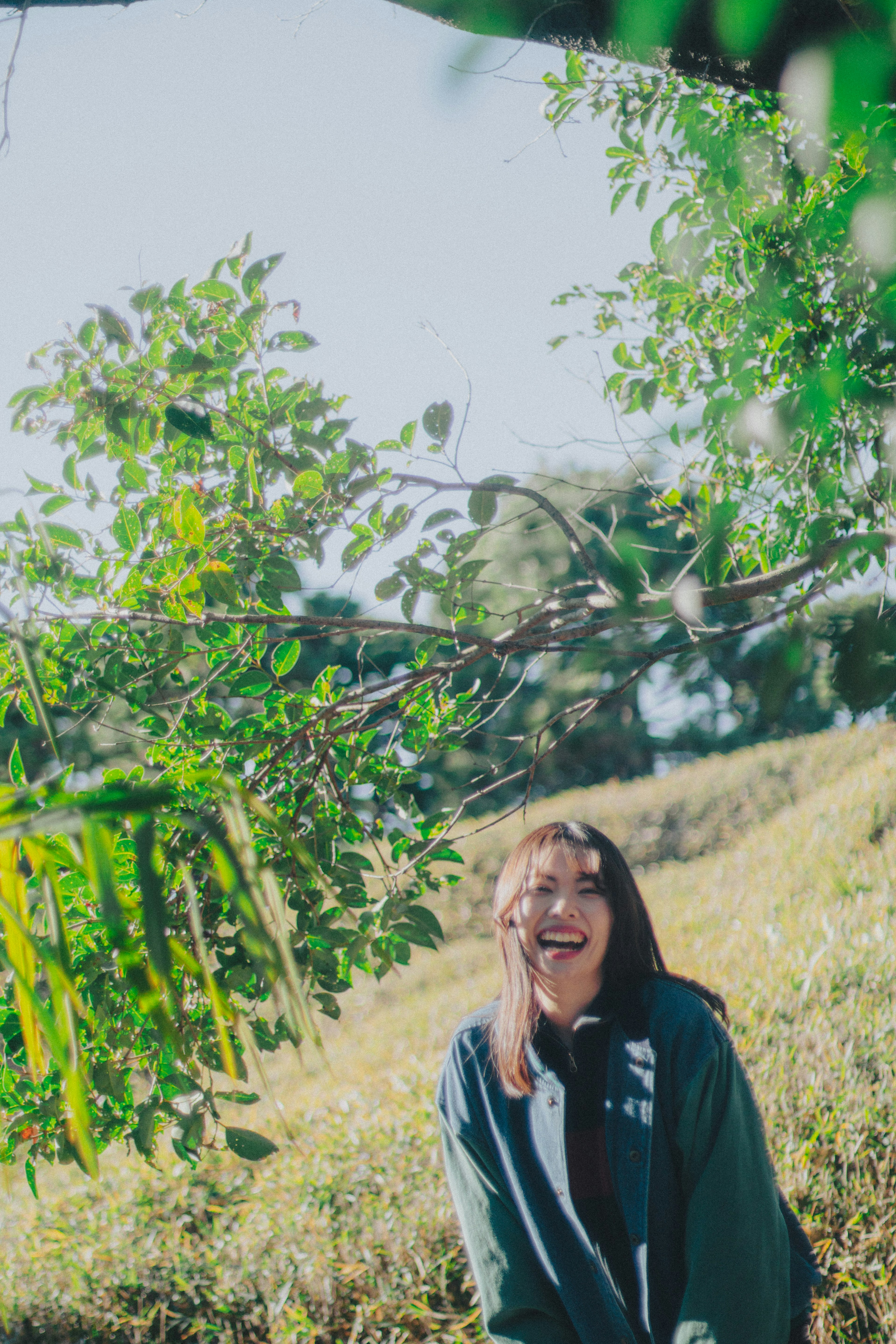 Una donna sorridente nella natura con luce solare brillante e vegetazione