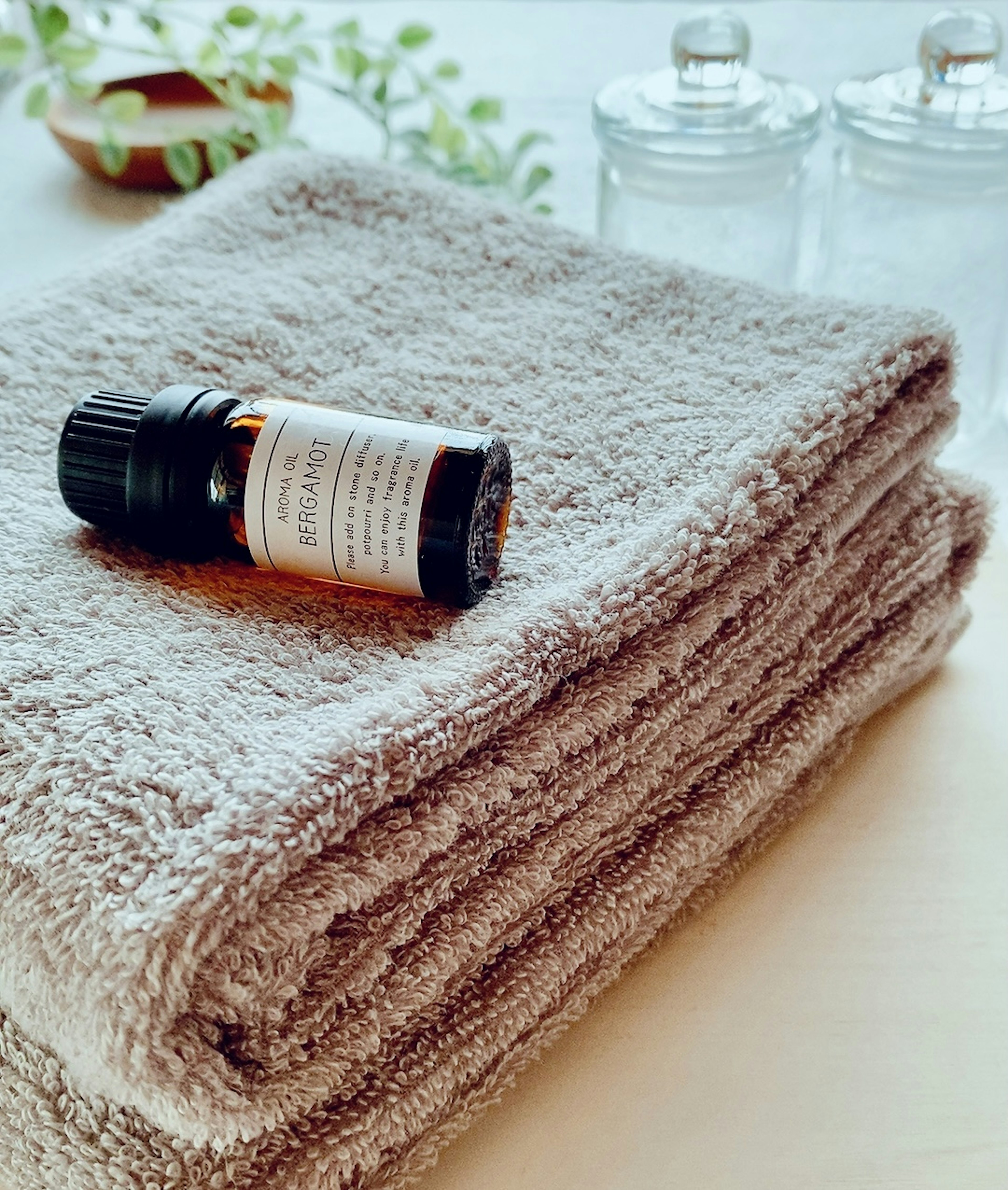 A soft towel with an essential oil bottle and clear glass containers in a serene setting