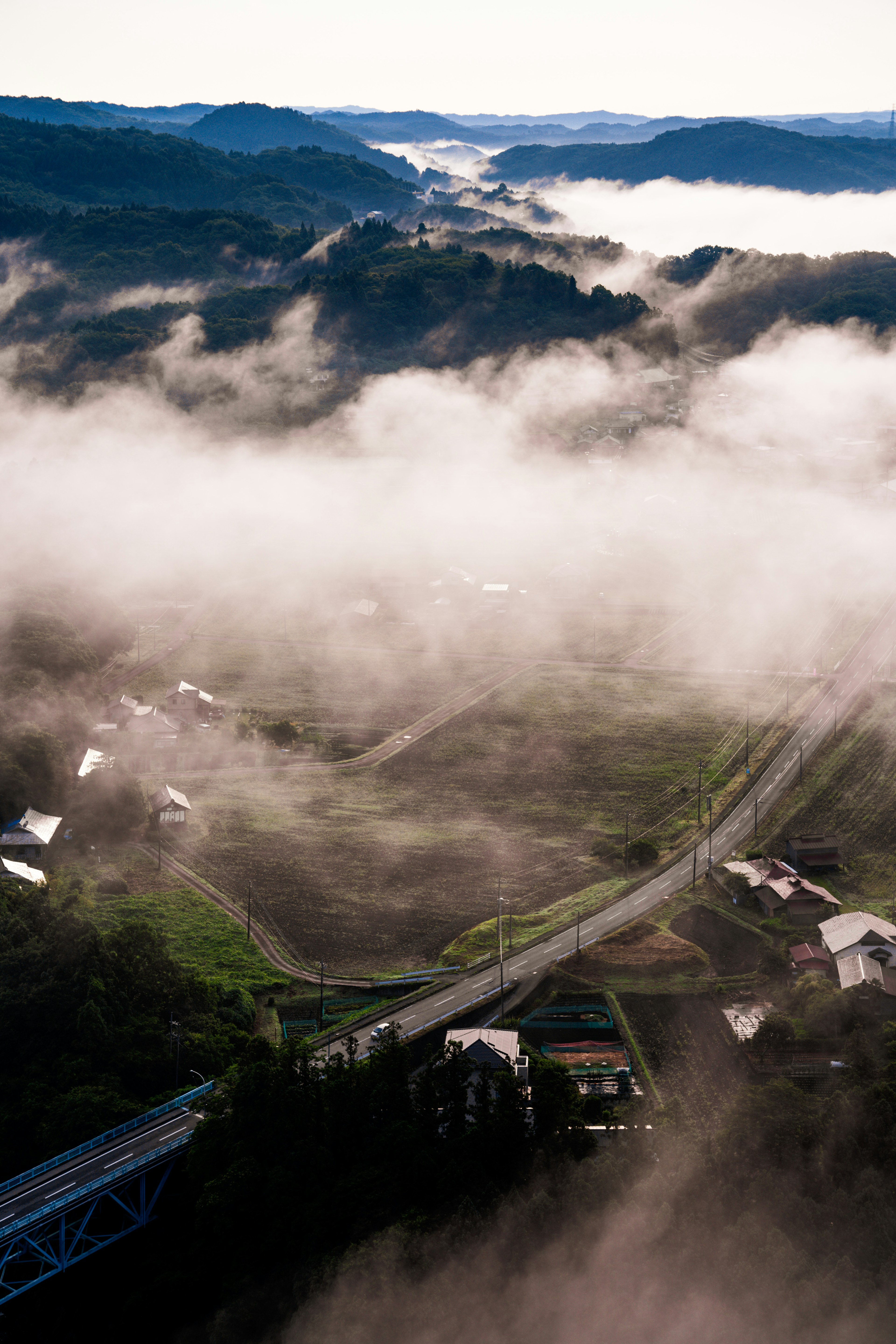 Vista aérea de montañas envueltas en niebla con carreteras sinuosas