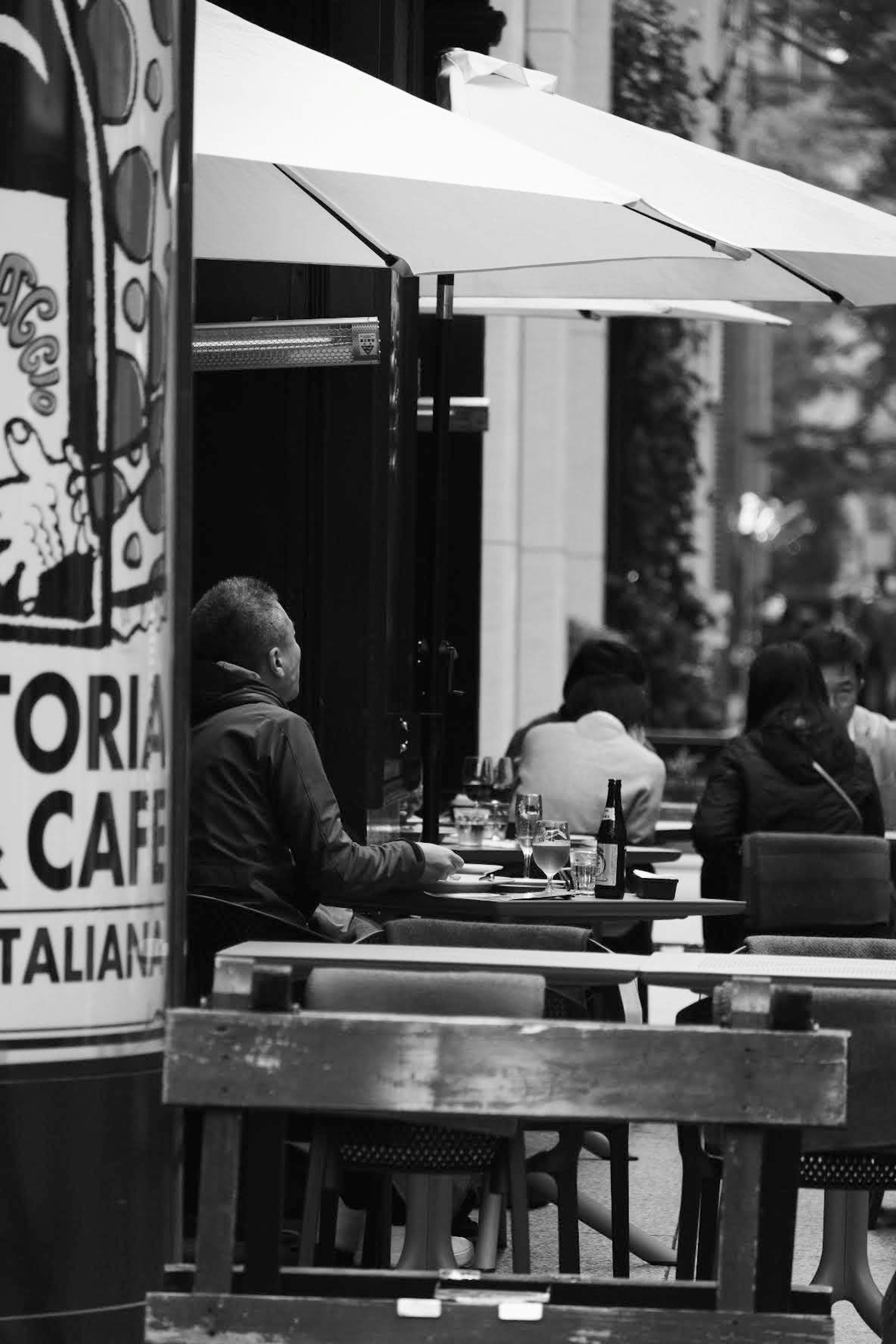 カフェのテラスで座っている人々のモノクロ写真