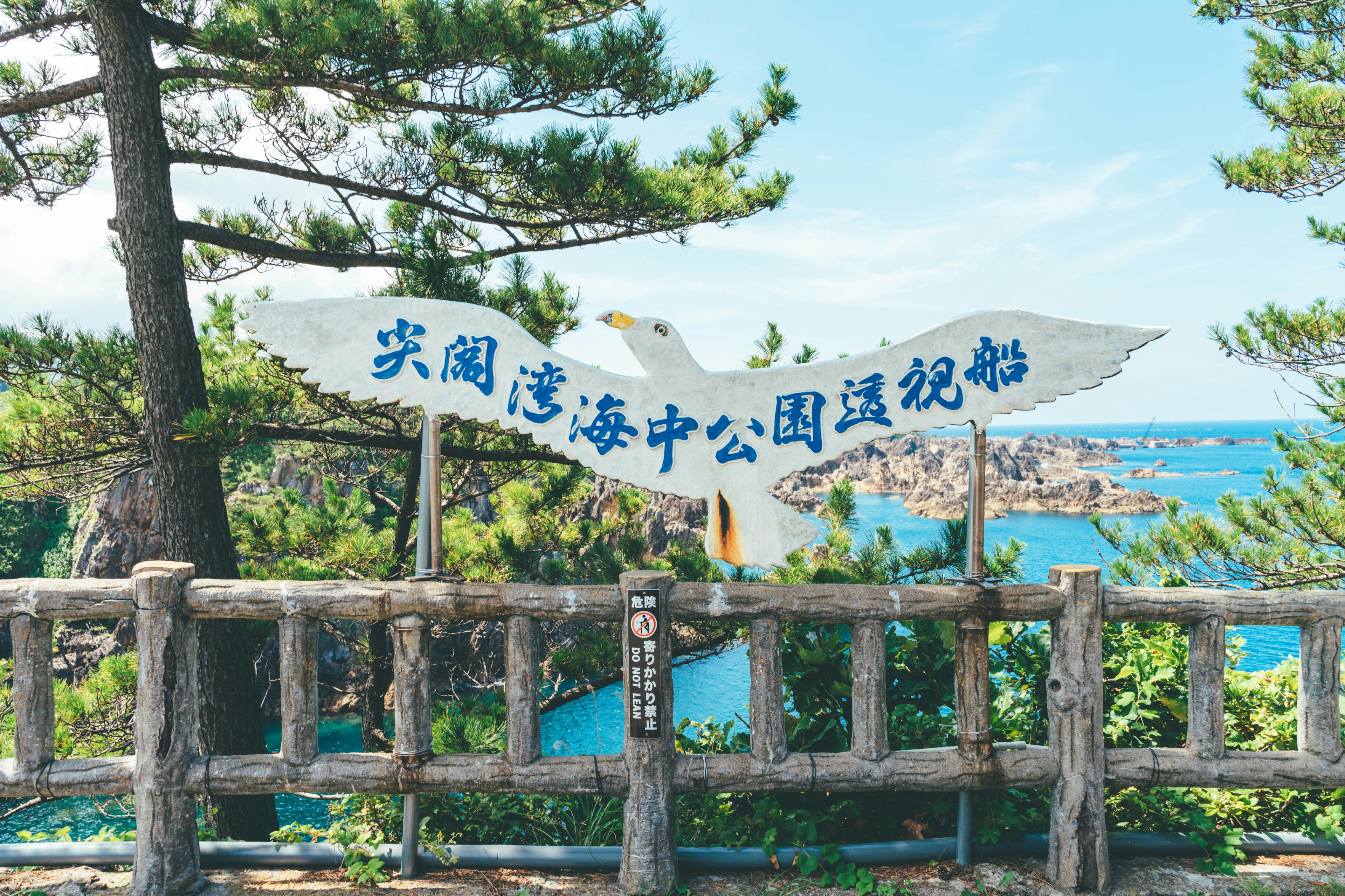 青い海と木々の間に立つ看板と美しい風景