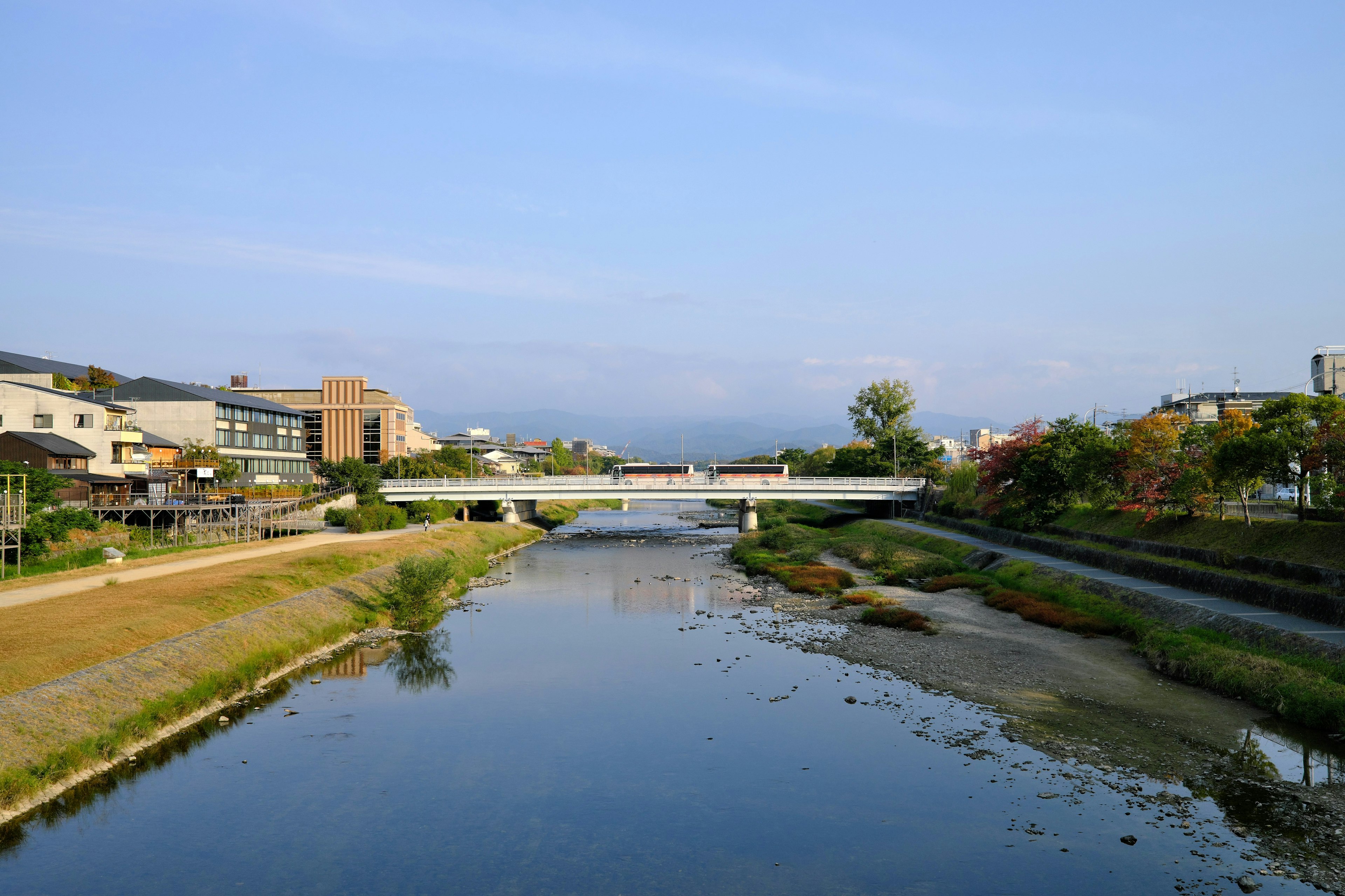 Vista escénica de un río tranquilo con un puente rodeado de edificios y vegetación