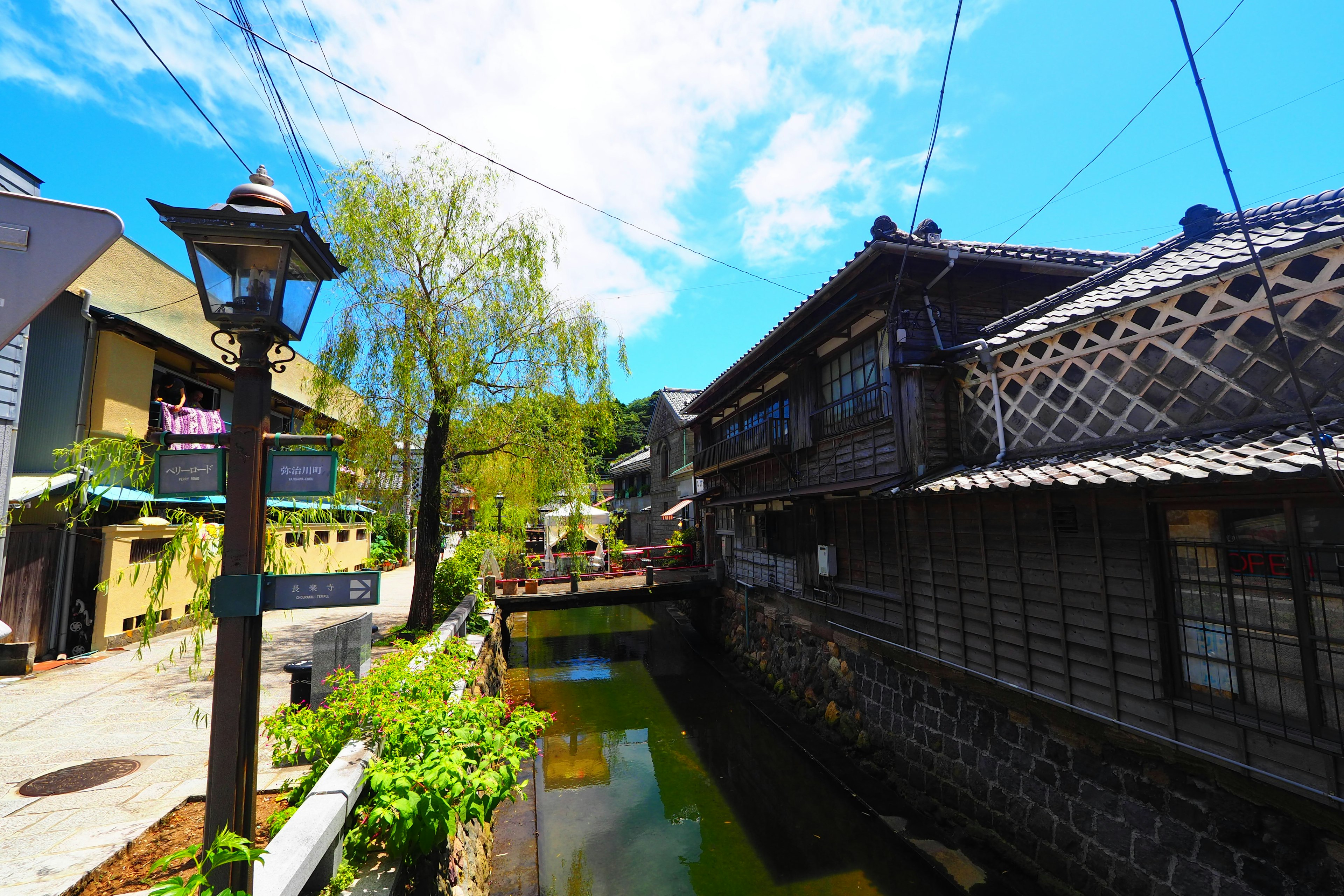 Traditional Japanese buildings along a river under a beautiful blue sky