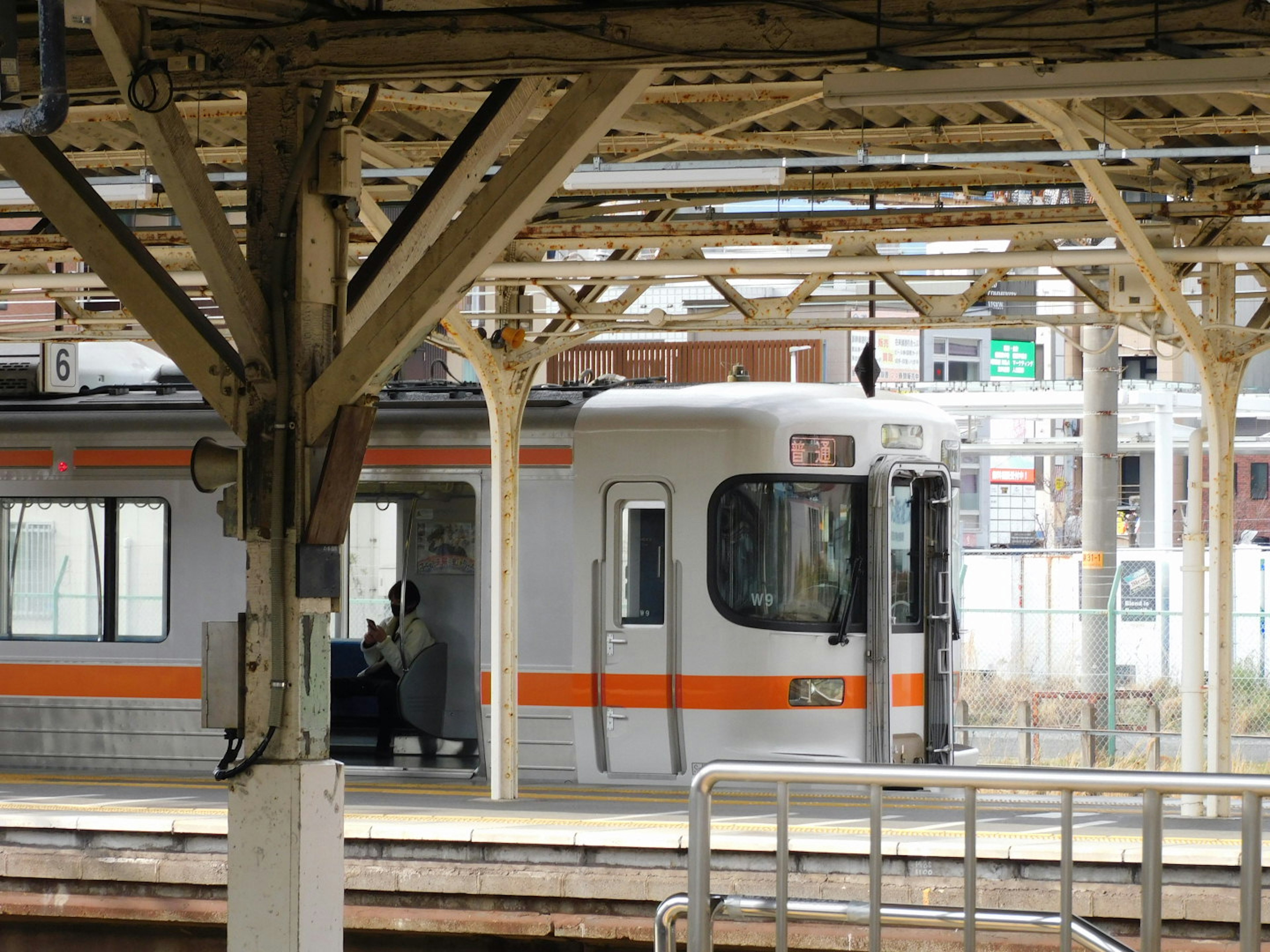 Tren con una franja naranja en una plataforma de estación