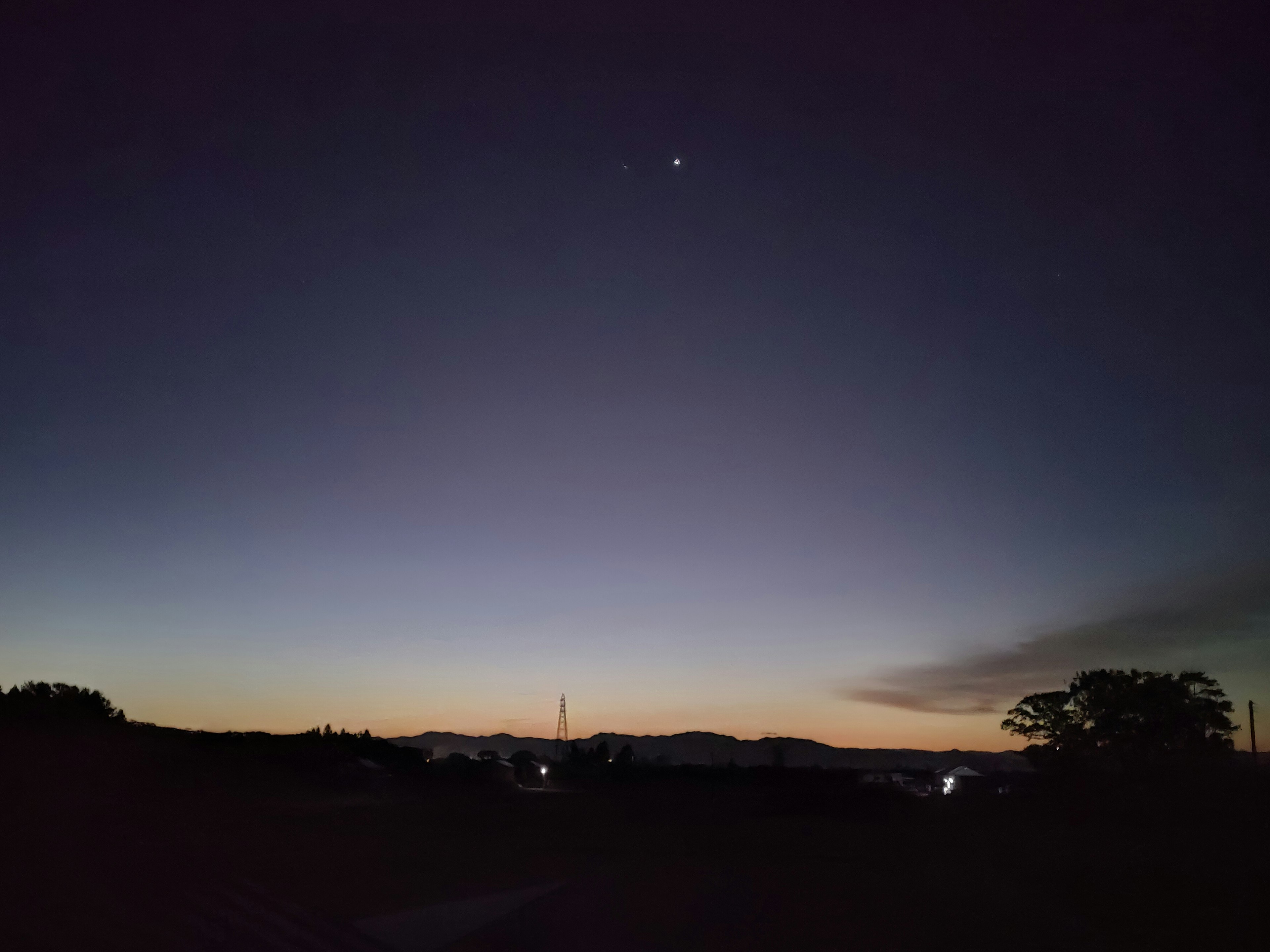 薄明かりの中の夜空に輝く星と山のシルエット