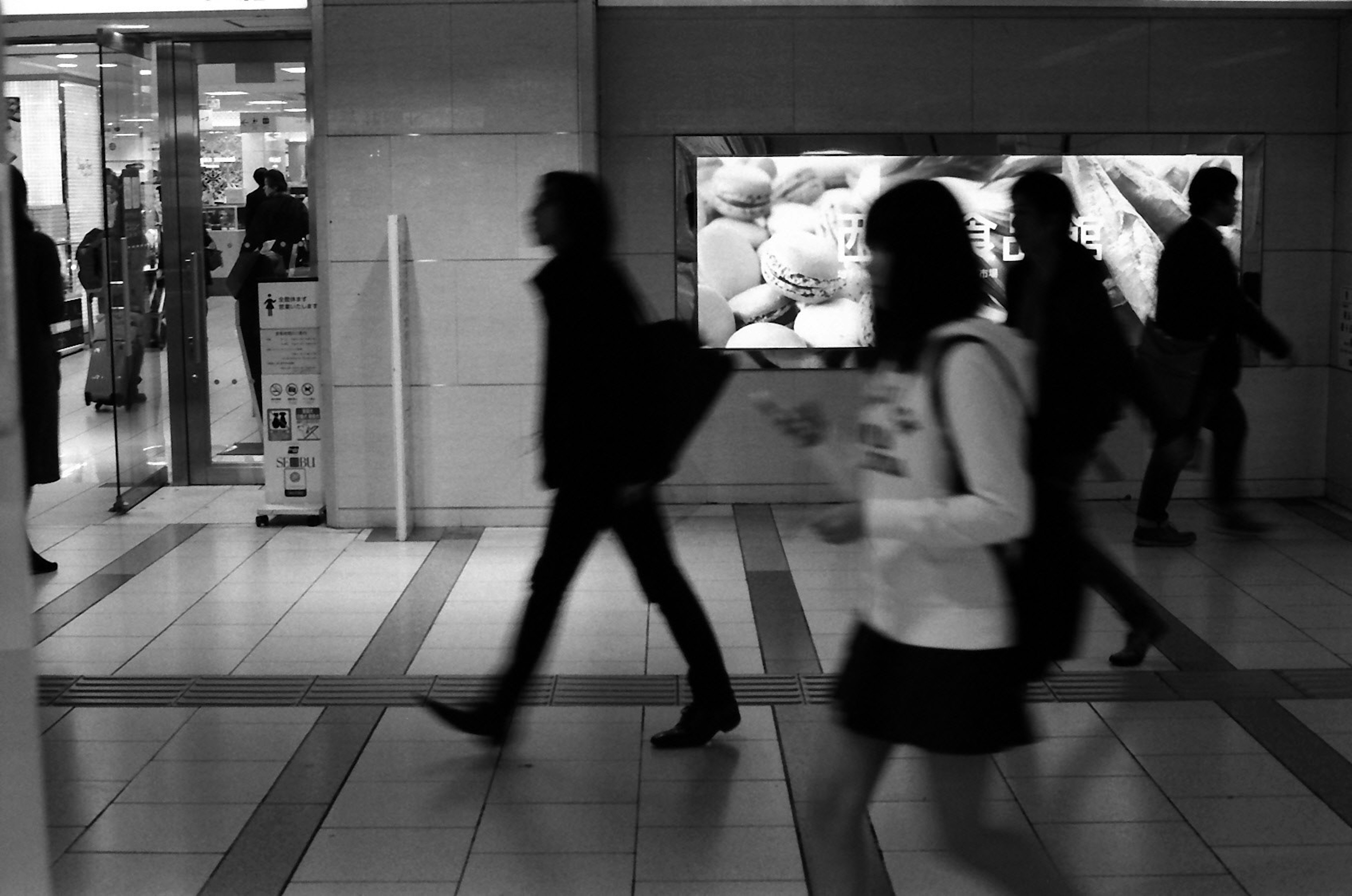 Escena urbana en blanco y negro de personas caminando en un centro comercial concurrido