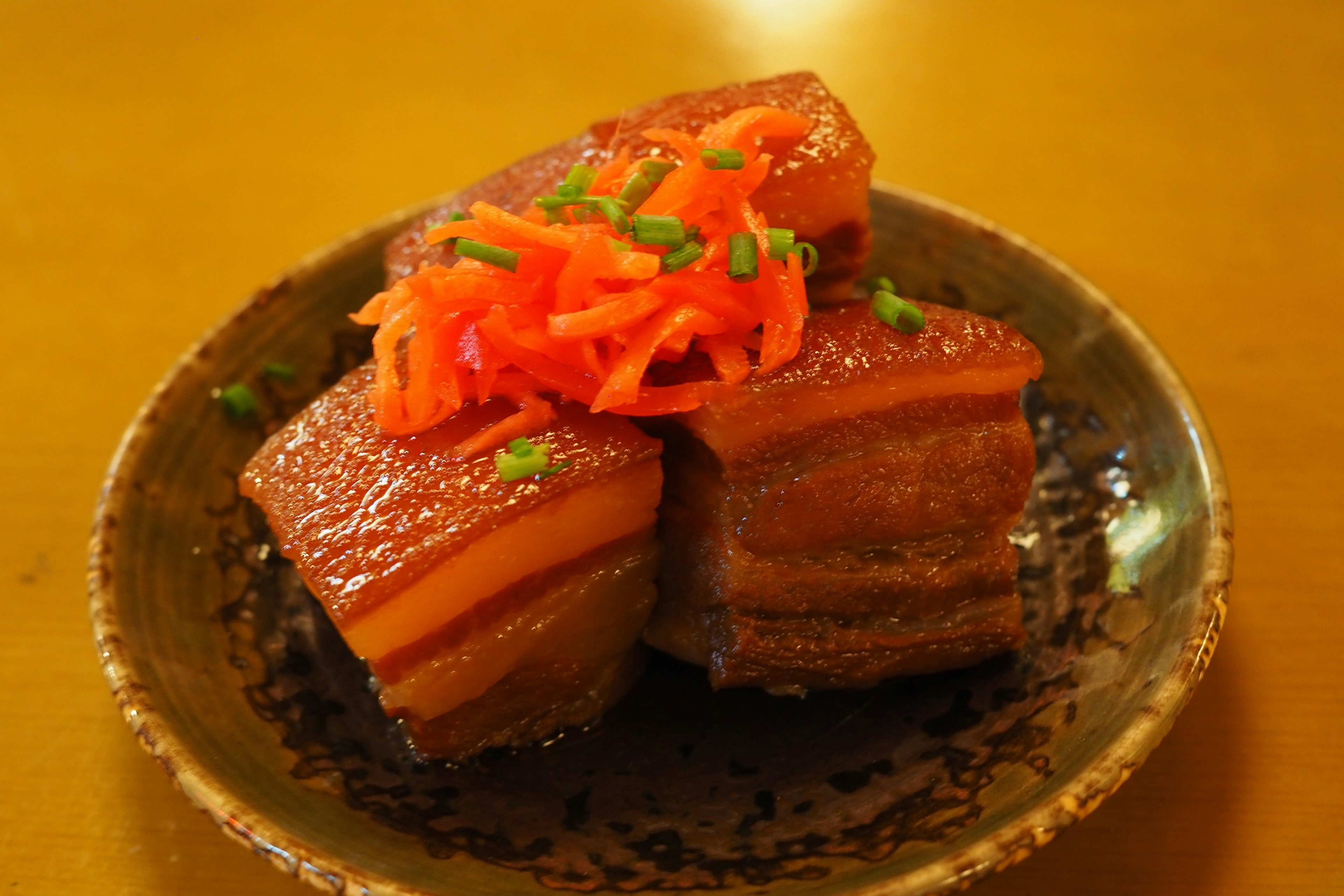 Delicious triangular pork dish topped with red ginger on a plate