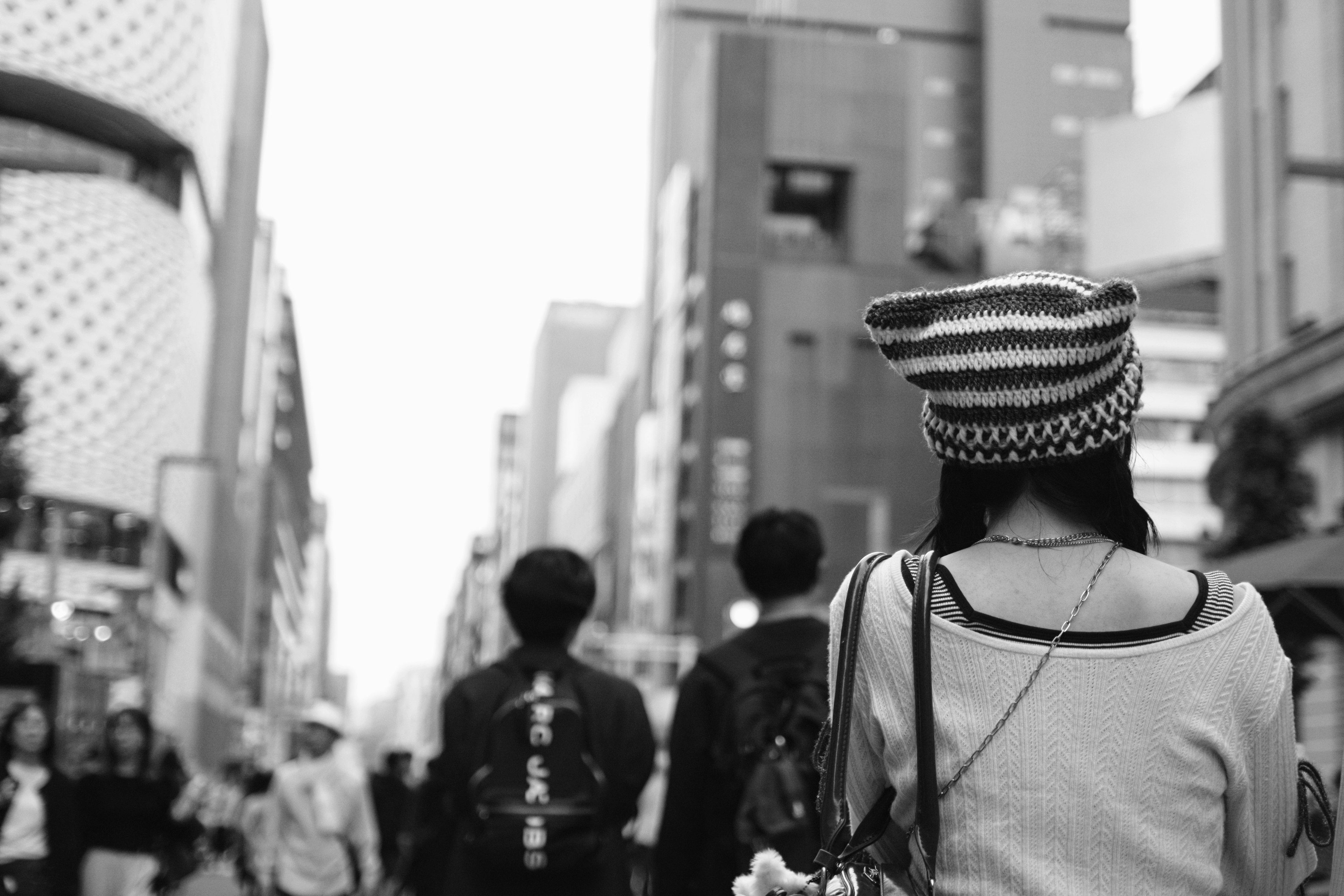 Femme marchant dans une rue de la ville de dos portant un chapeau rayé dans un cadre monochrome