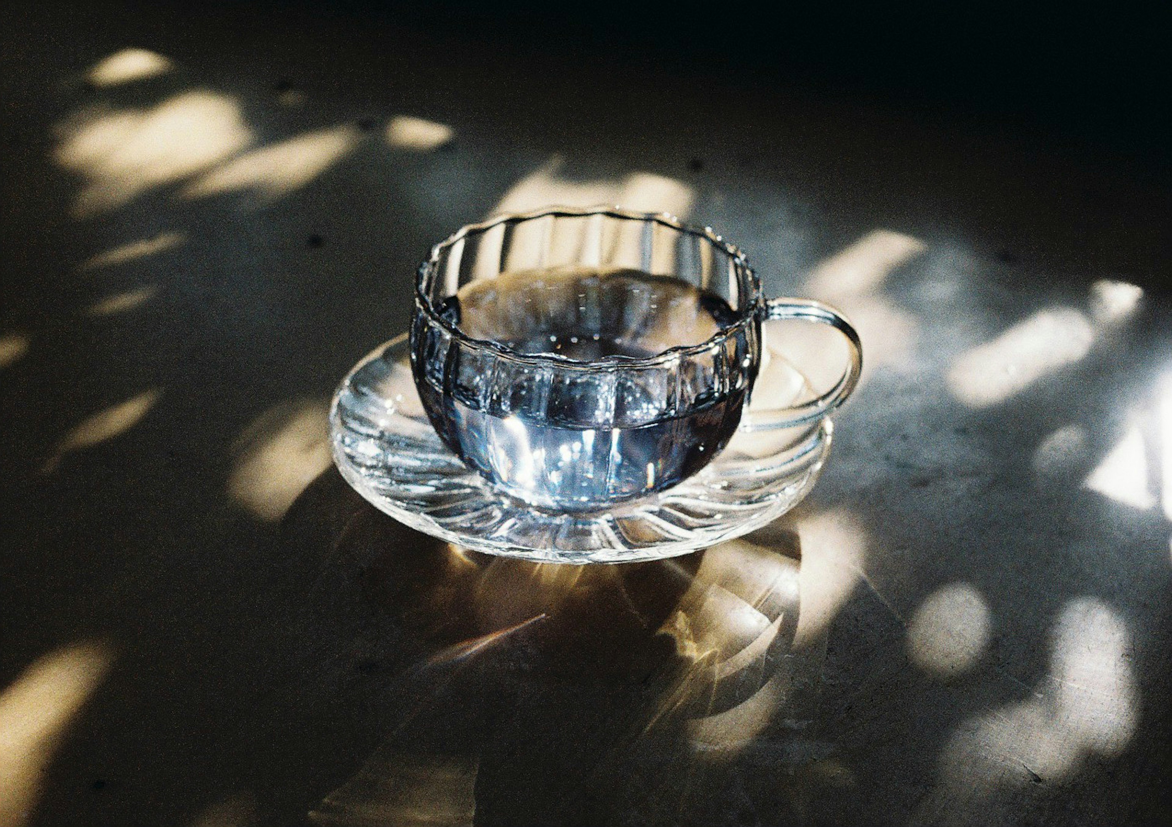 Une tasse en verre transparent avec une soucoupe posée sur une table