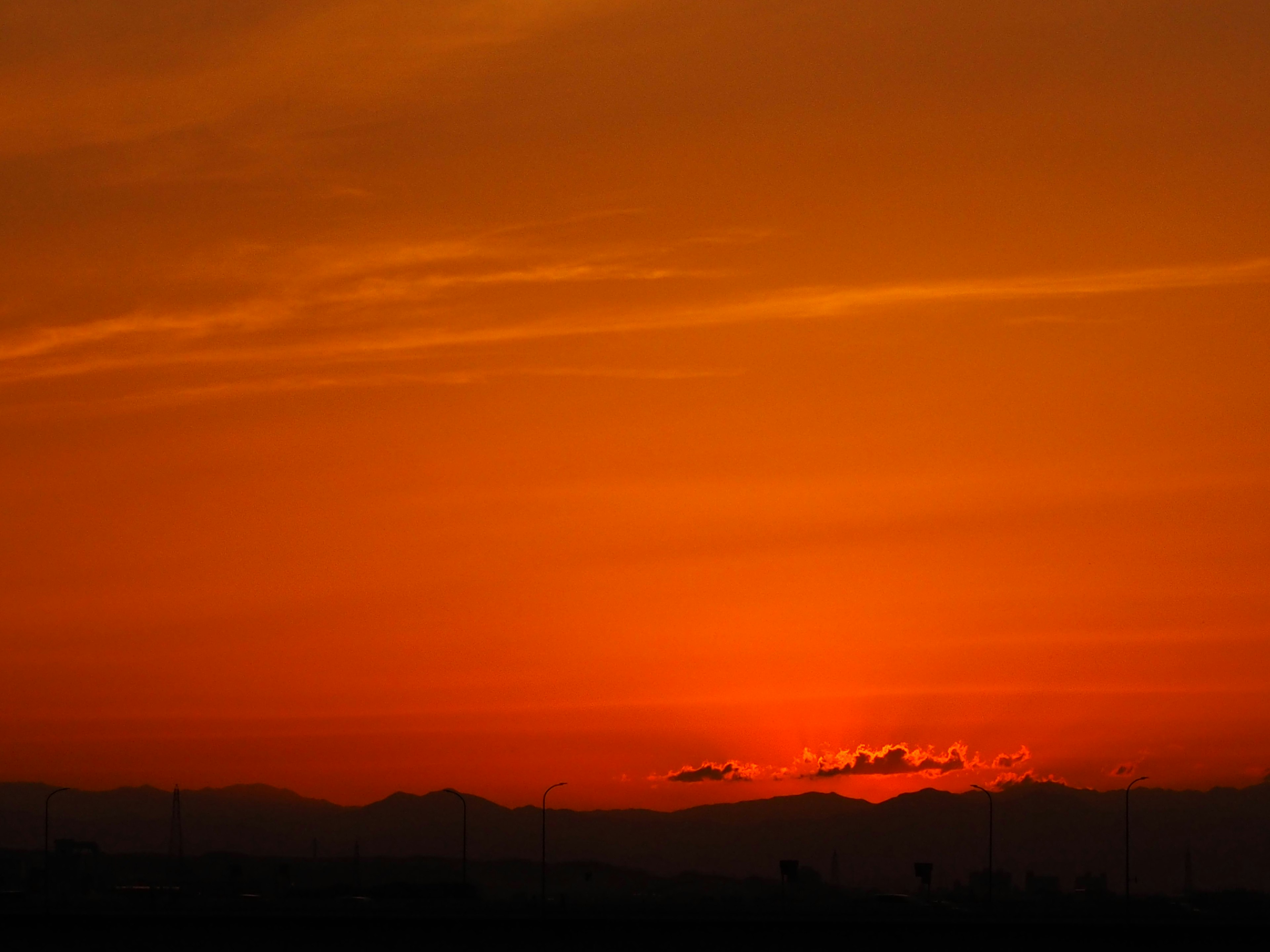 Cielo naranja al atardecer con montañas distantes