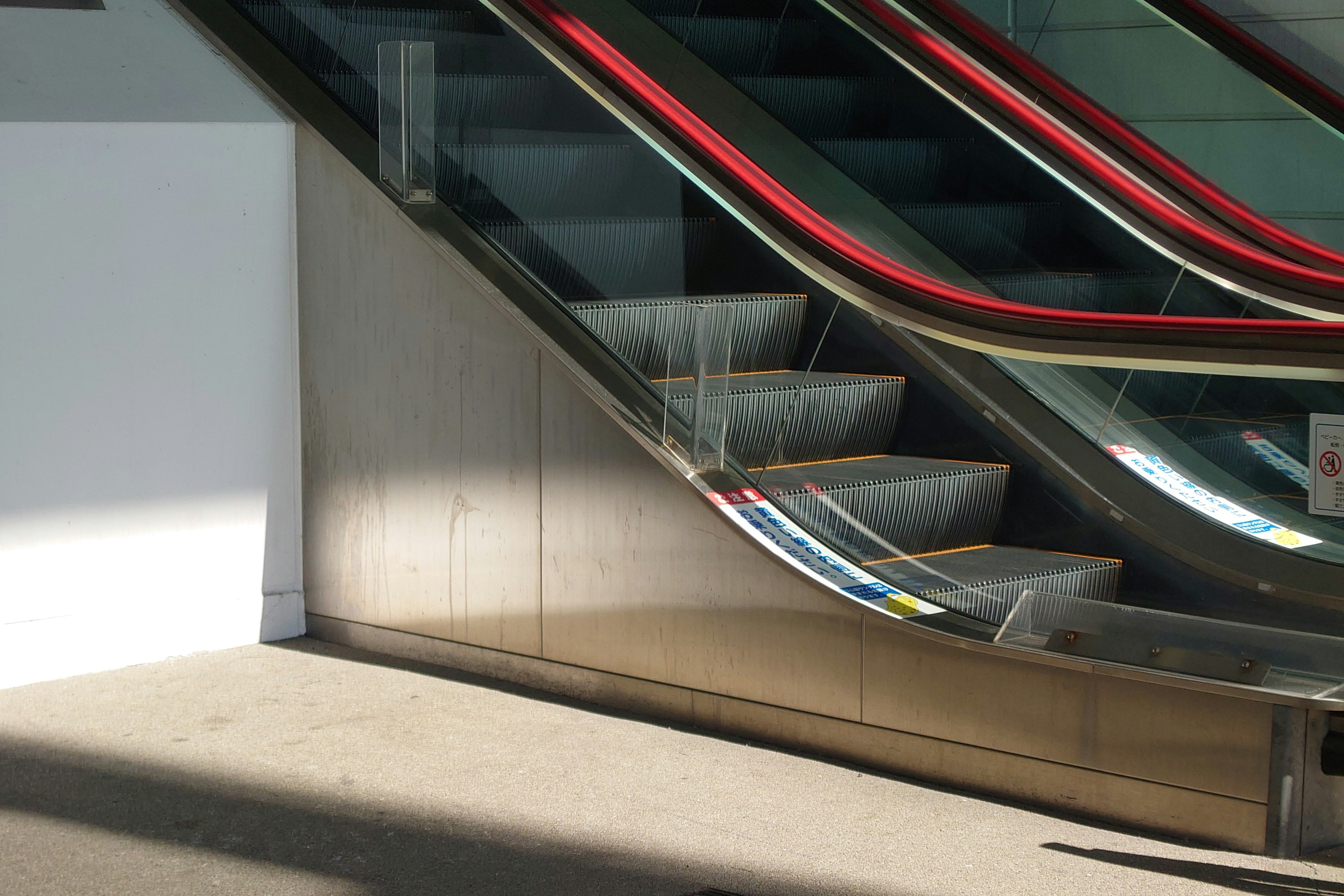 A partial view of an escalator with structural elements Bright light contrasts with shadows