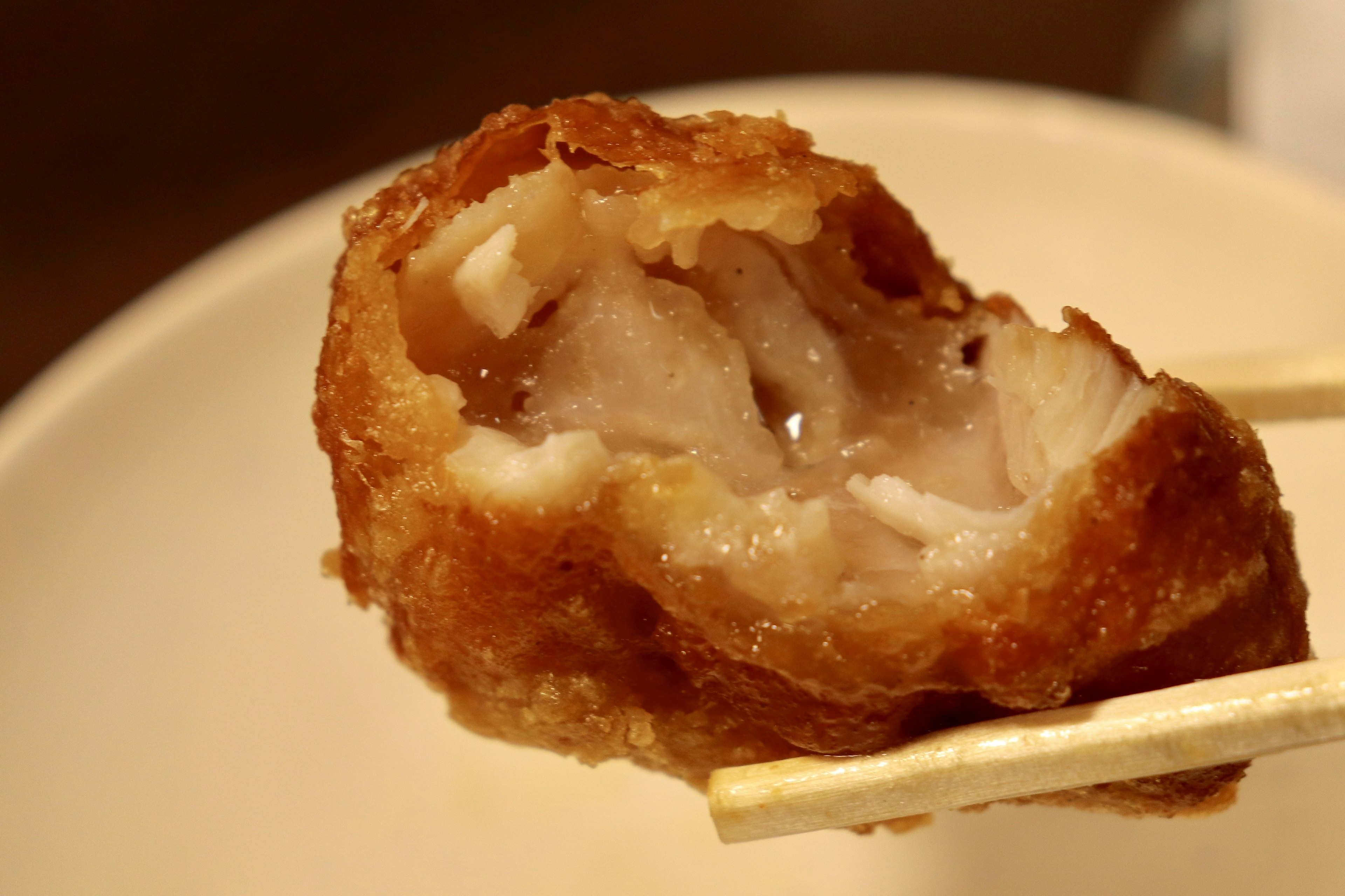 Close-up of fried chicken piece held by chopsticks