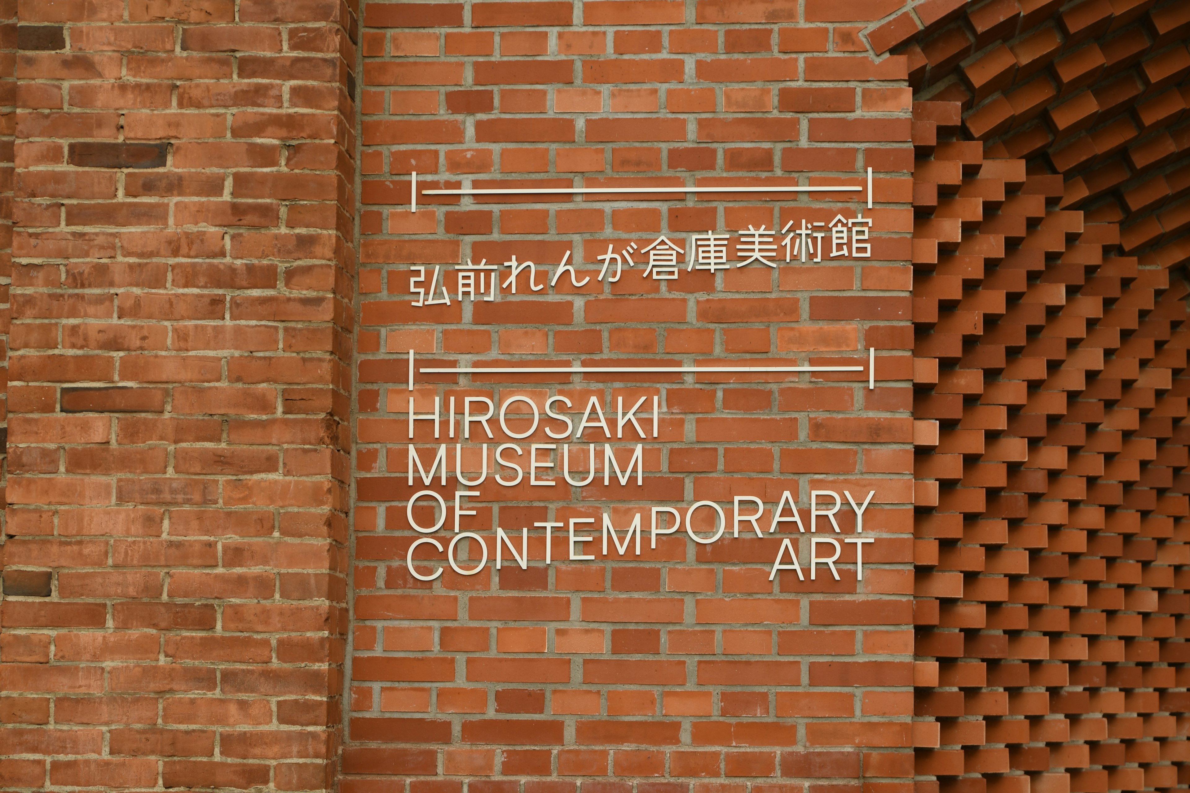 Cartel del Museo de Arte Contemporáneo de Hirosaki en una pared de ladrillos