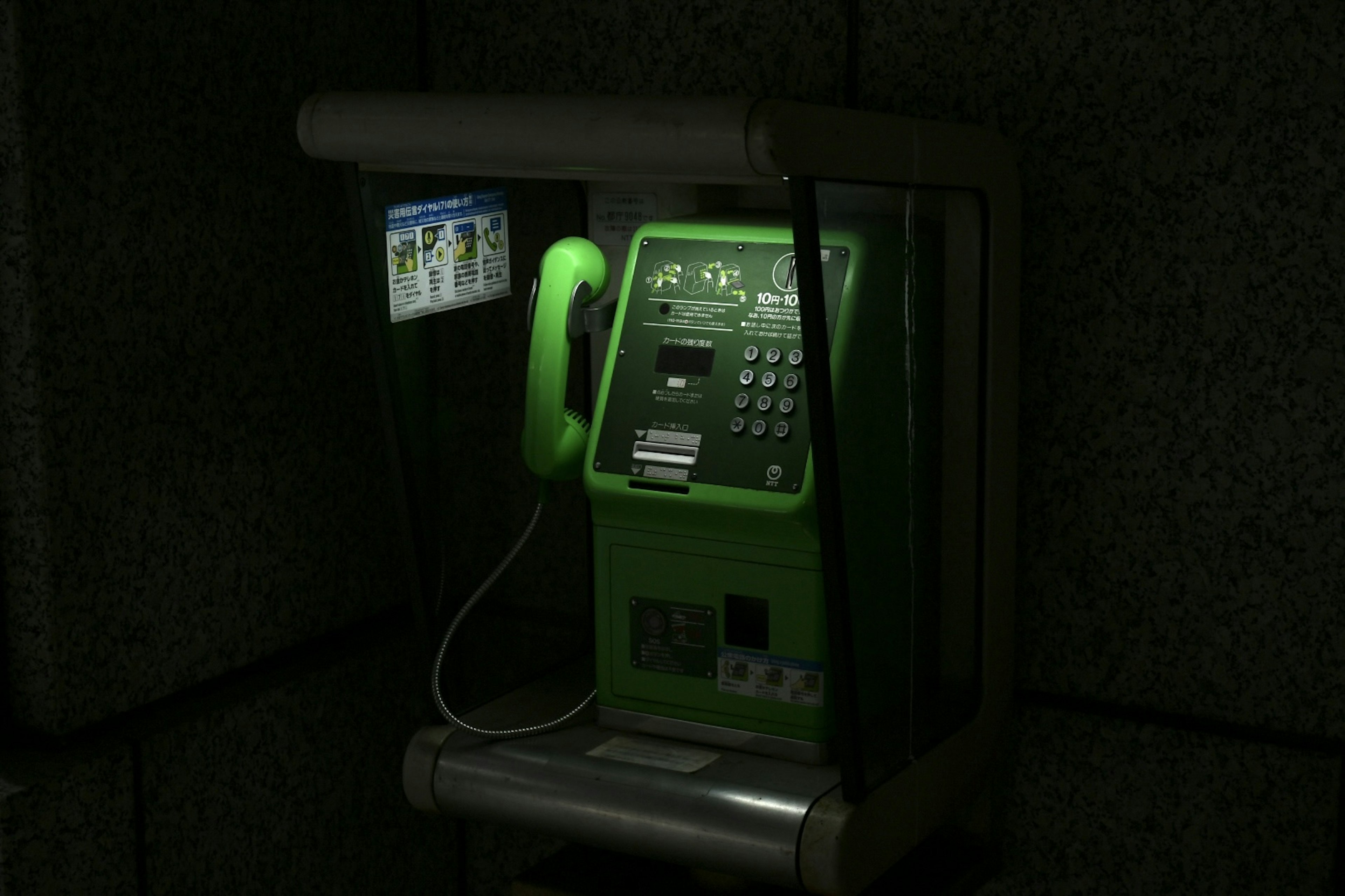 Cabine téléphonique publique verte installée sur un fond sombre