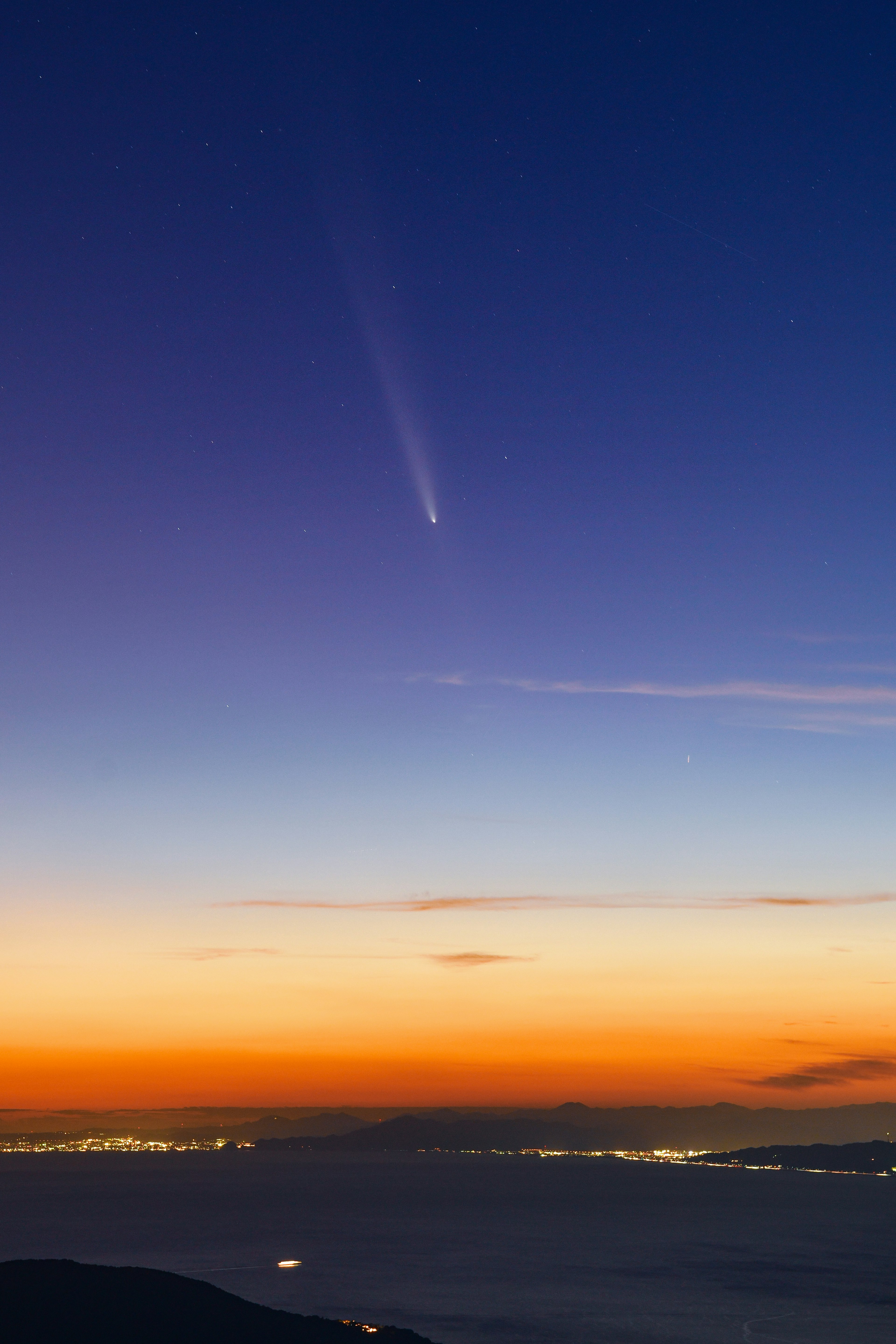 Comet visible in the sunset sky over the ocean