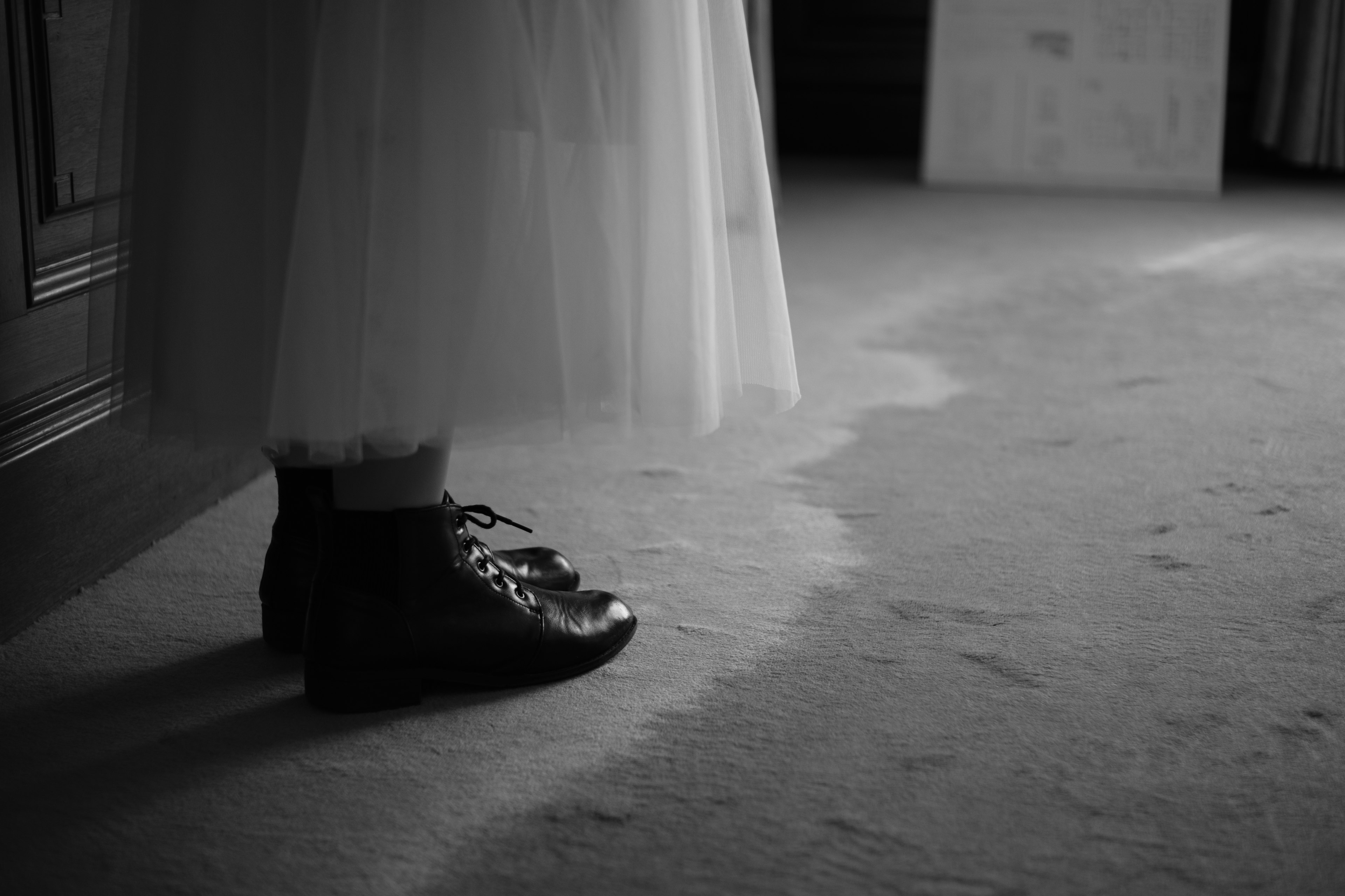 Zapatos negros de una persona con una falda de tul blanca en una foto en blanco y negro