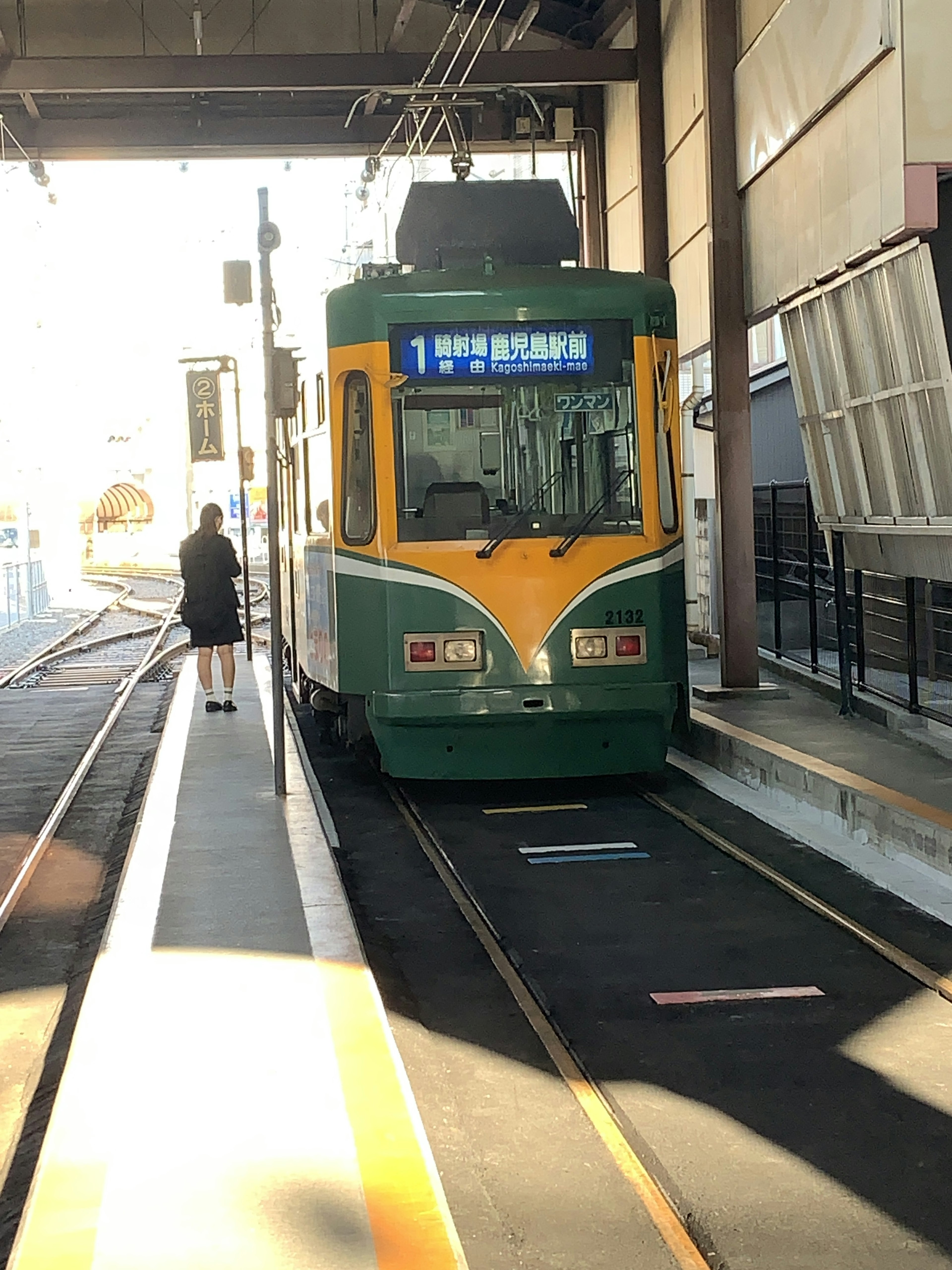 緑と黄色のトラムが駅に停車している