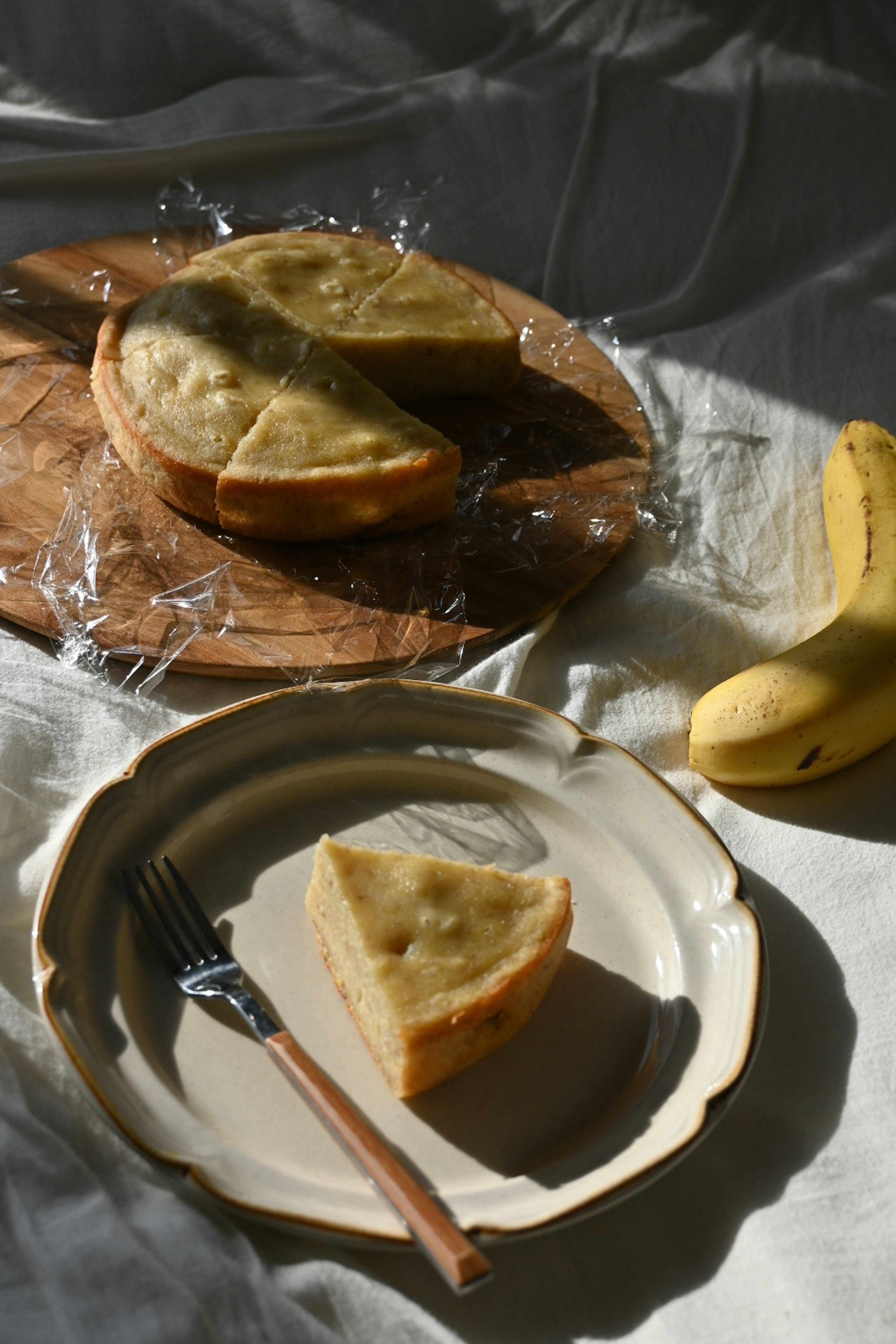 Sliced banana cake on a wooden board with a banana nearby