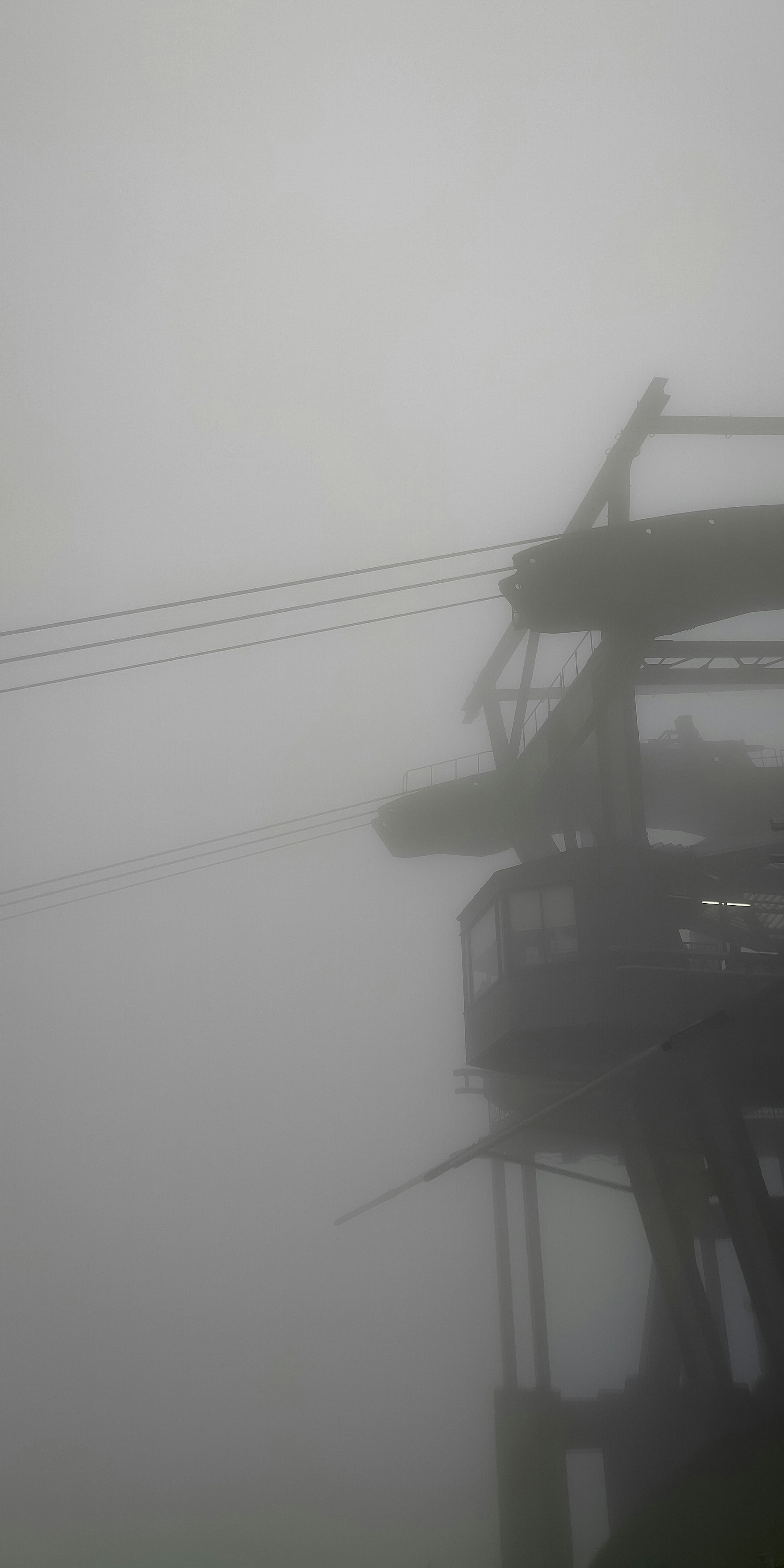 Torre de teleférico y cables en la niebla