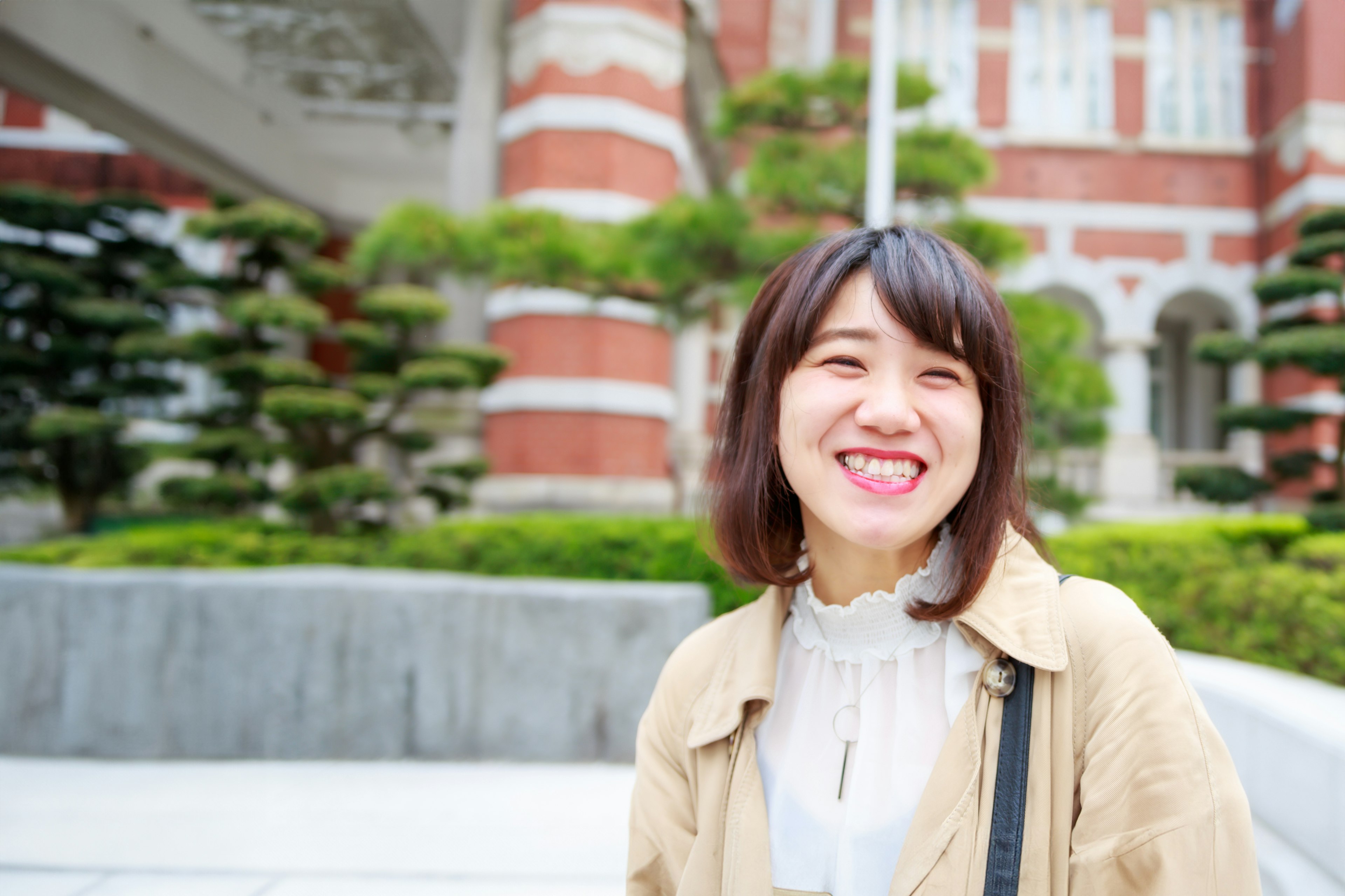 Seorang wanita tersenyum berdiri di depan bangunan bersejarah di Jepang