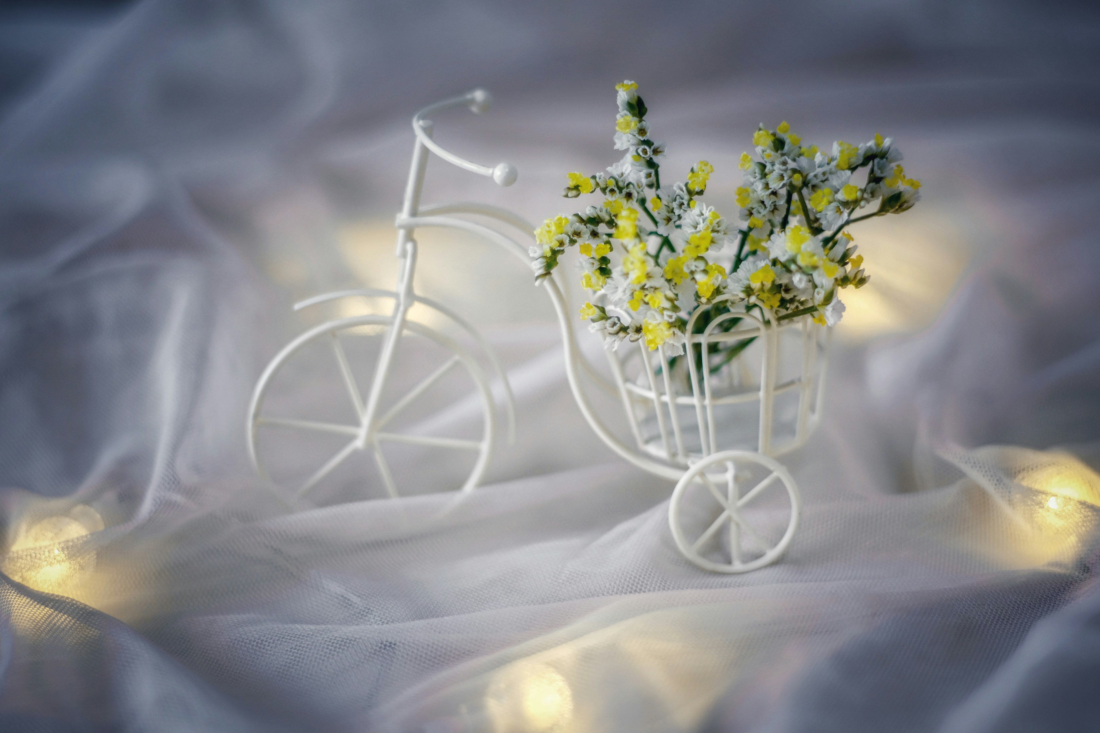 Un vase en forme de bicyclette blanche contenant de petites fleurs jaunes dans un cadre intérieur serein