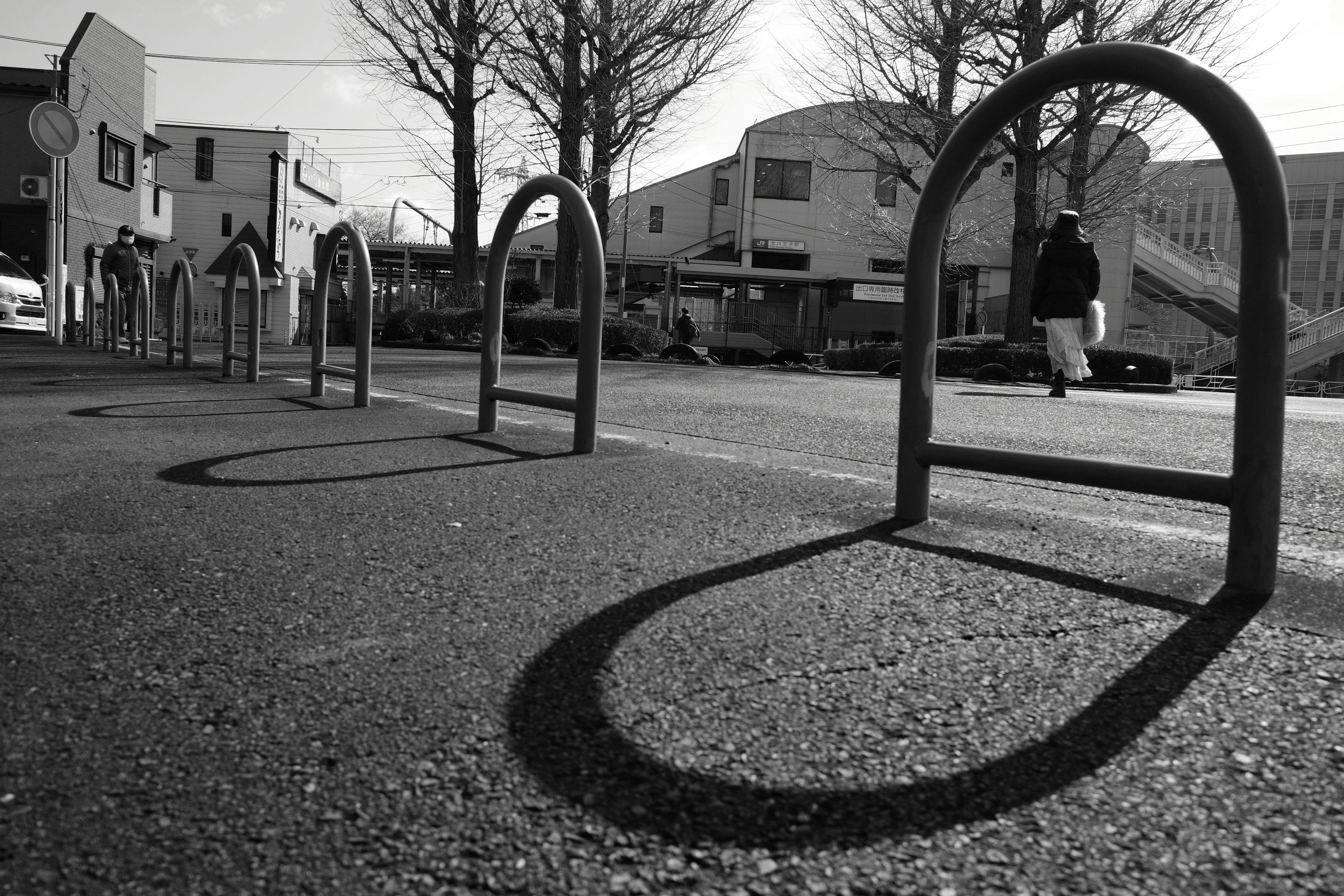 Bicycle racks casting shadows on the road with nearby buildings