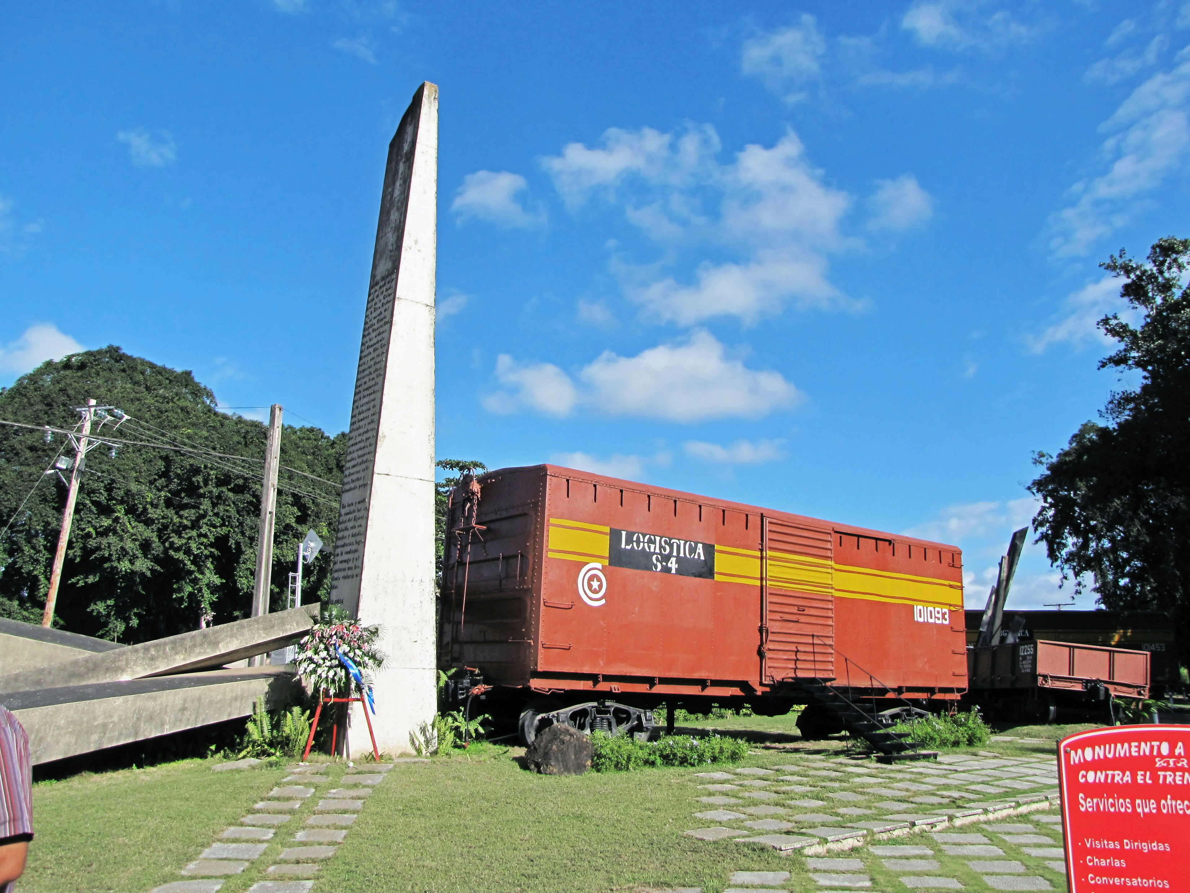 Un wagon de train de marchandises rouge à côté d'un monument sous un ciel bleu