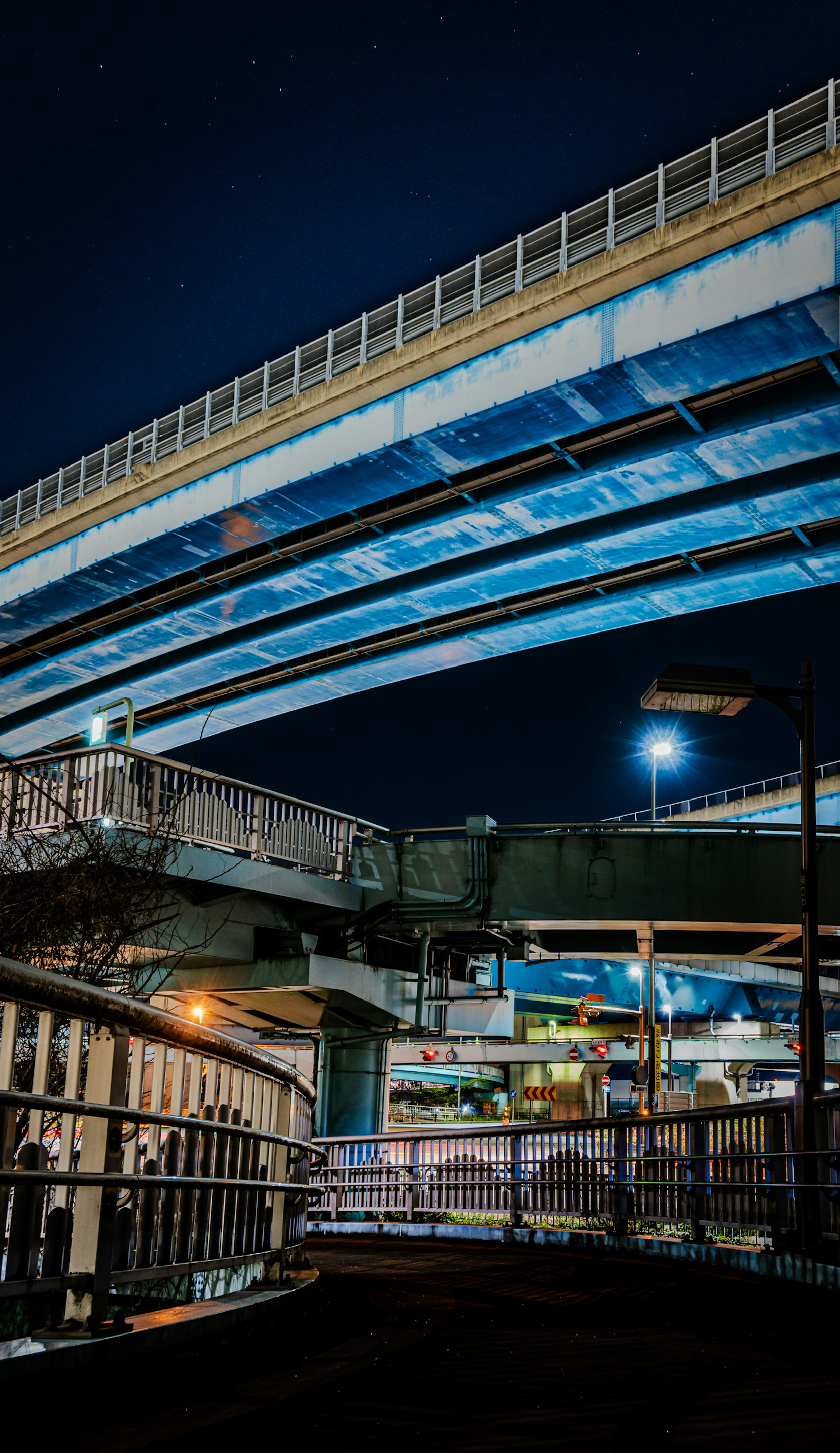 Struktur jembatan saling bersilangan terlihat dari bawah di pemandangan kota malam