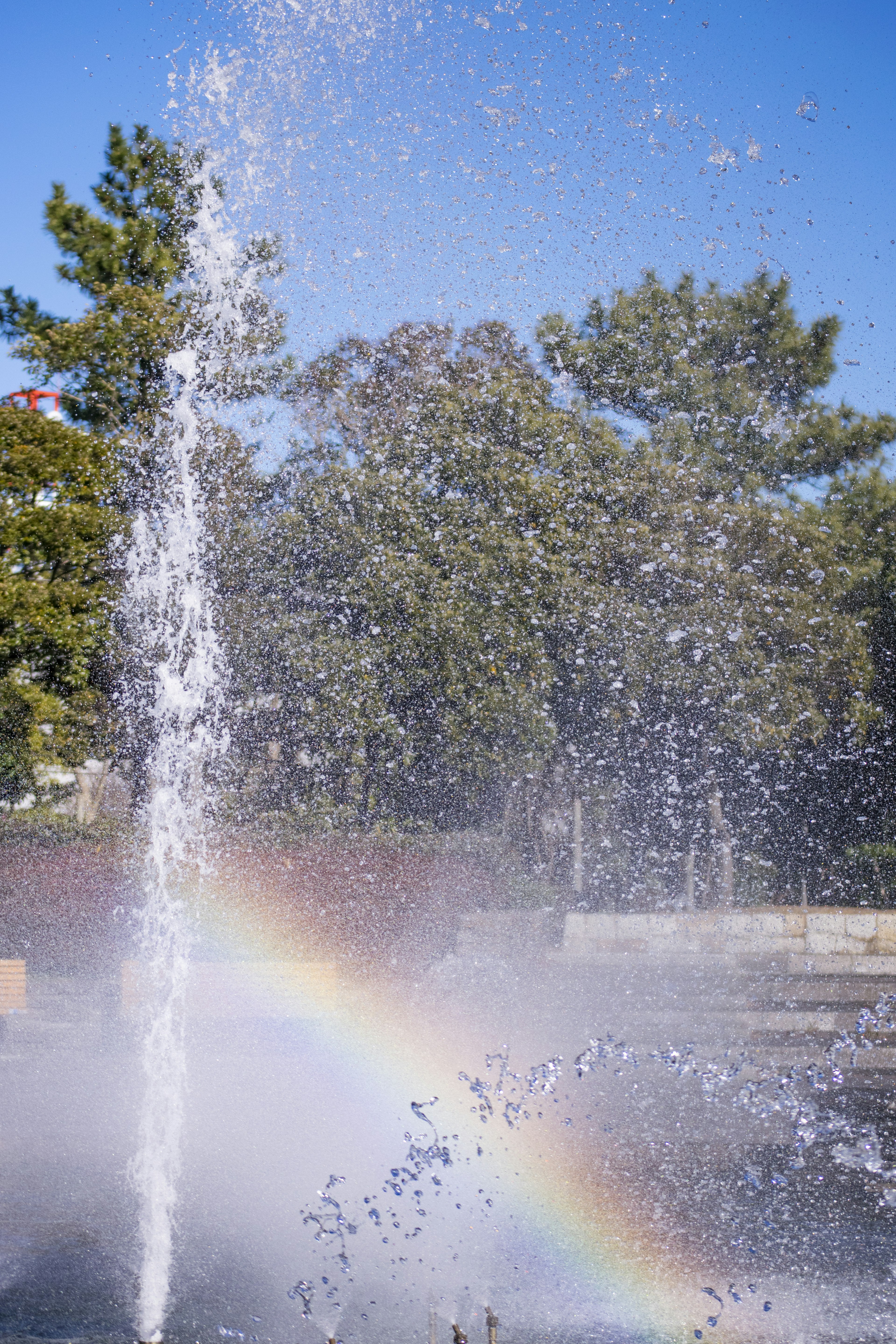 Parkszene mit einem Brunnen, Wasserspritzern und einem Regenbogen