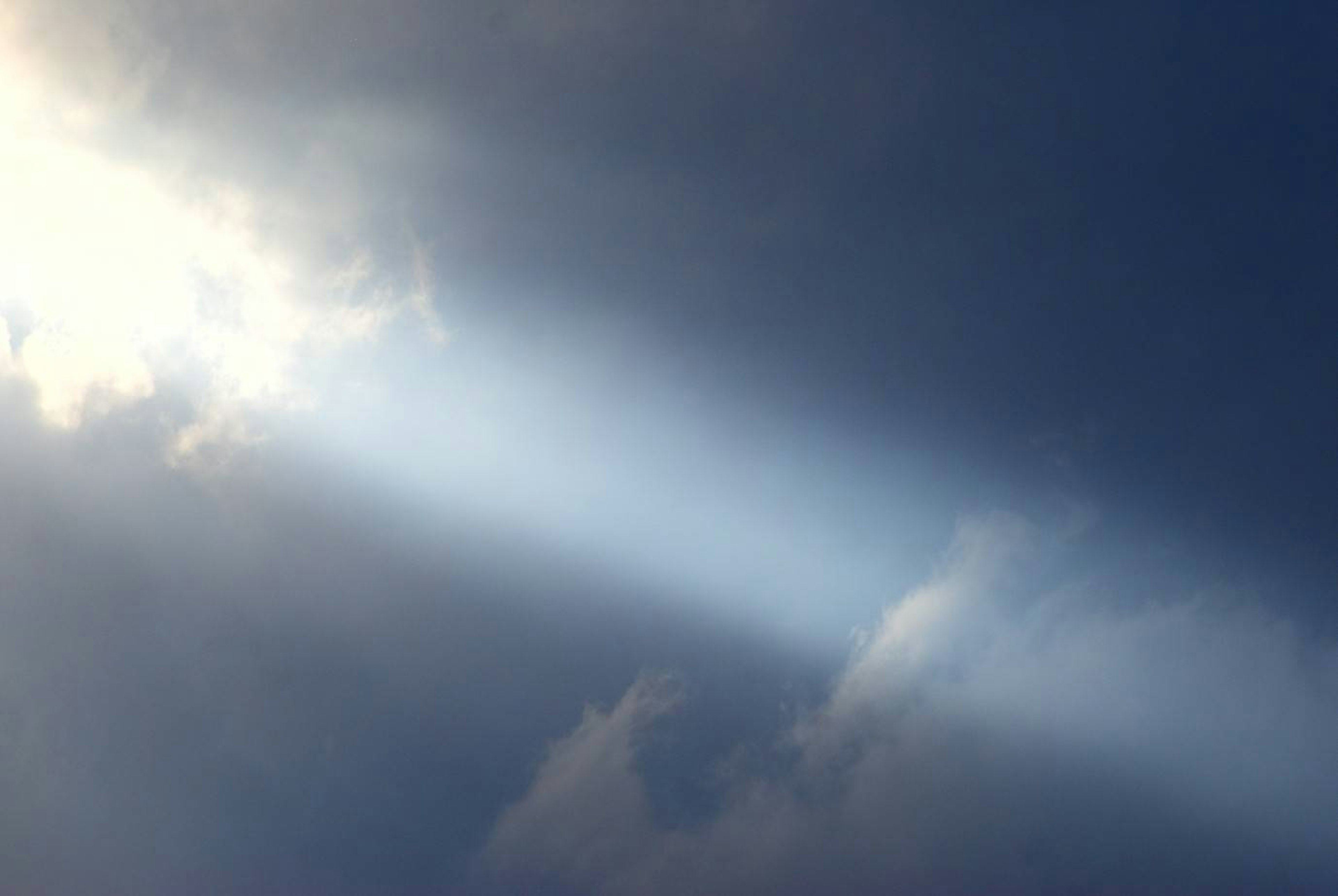 Beam of light shining through clouds in a blue sky